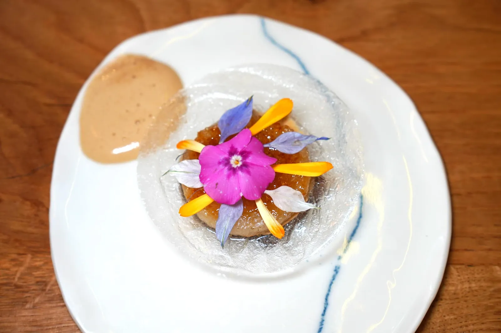 Texture pudding au jus de viande, tamarin-hibiscus, pomme nashi ในจานสีขาวคือ Textures of Canelé ที่เชฟแยกองค์ประกอบมาใหม่เพื่อให้เกิดความแตกต่างโดยมีกลิ่นหอมของกาแฟ แผ่นสีใสด้านบนคือ Crystalized Rice กรอบ ๆ และ Nashi Apple หรือลูกแพร์ ส่วนครีมข้าง ๆ เตรียมมาจากมะขามและดอกชบา (19/20)