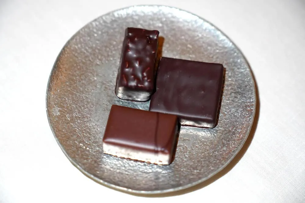 Mignardises จากนั้นพนักงานจะนำเสิร์ฟขนมหวานชิ้นเล็ก ๆ ปิดท้ายเพื่อรับประทานคู่กับ Infusion เป็น Chocolates จาก Alain Ducasse Factory โดยประกอบไปด้วยช็อกโลแลตจาก Sicily, Peru และช็อกโกแลตที่มีส่วนผสมของ Tonka Bean