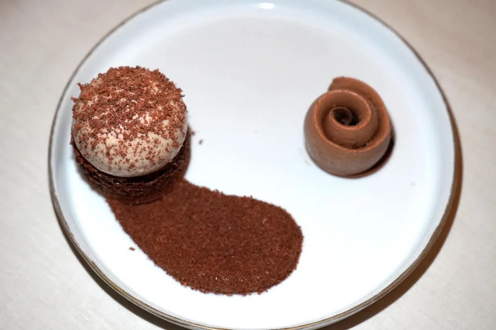 Chocolat Java de notre Manufacture, poivre sauvage, granité grué (40 €) Java chocolate from our Manufacture, wild pepper, cocoa nib granité เริ่มจากฝั่งซ้ายมือคือบิสกิตทำมาจากถั่ว Hazelnut เมื่อตักรับประทานแล้วแทบจะละลายได้ในปาก ด้านบนคือองค์ประกอบของ Java Chocolate รสชาติขมแทรกด้วยรสเปรี้ยวทั้งยังมีเนื้อสัมผัสที่เบาละมุน ข้างกันคือไอศกรีมช็อกโกแลตที่โรยด้านบนด้วยผงพริกไทยป่าให้อโรม่าฟุ้งขึ้นจมูกเข้ากันกับช็อกโกแลตได้อย่างน่าตกใจ (18/20)