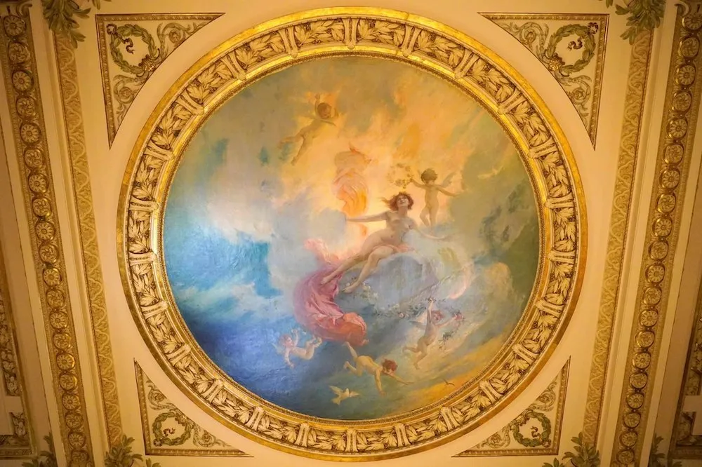 เบื้องหลังโคมระย้าคือภาพวาด Fresco รูปหญิงสาวที่กำลังล่องลอยอยู่กลางอากาศรายล้อมด้วยเหล่ากามเทพตัวน้อย