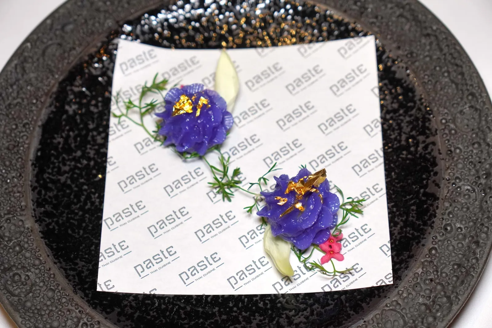 ช่อม่วงโบราณ Amuse-bouche เริ่มต้นมื้ออาหารด้วยจานเรียน้ำย่อยอย่างช่อม่วงที่พับจับจีบได้อย่างปราณีตสวยงาม แป้งเนื้อนุ่มหนึบ ตกแต่งด้วยดอกไม้รับประทานได้ ด้านในสอดไส้เนื้อปลาเทร้าต์ที่ผ่านการรมควันจนหอม รสชาติละมุนเนียนไปกับแป้งช่อม่วงได้อย่างลงตัว (15/20)