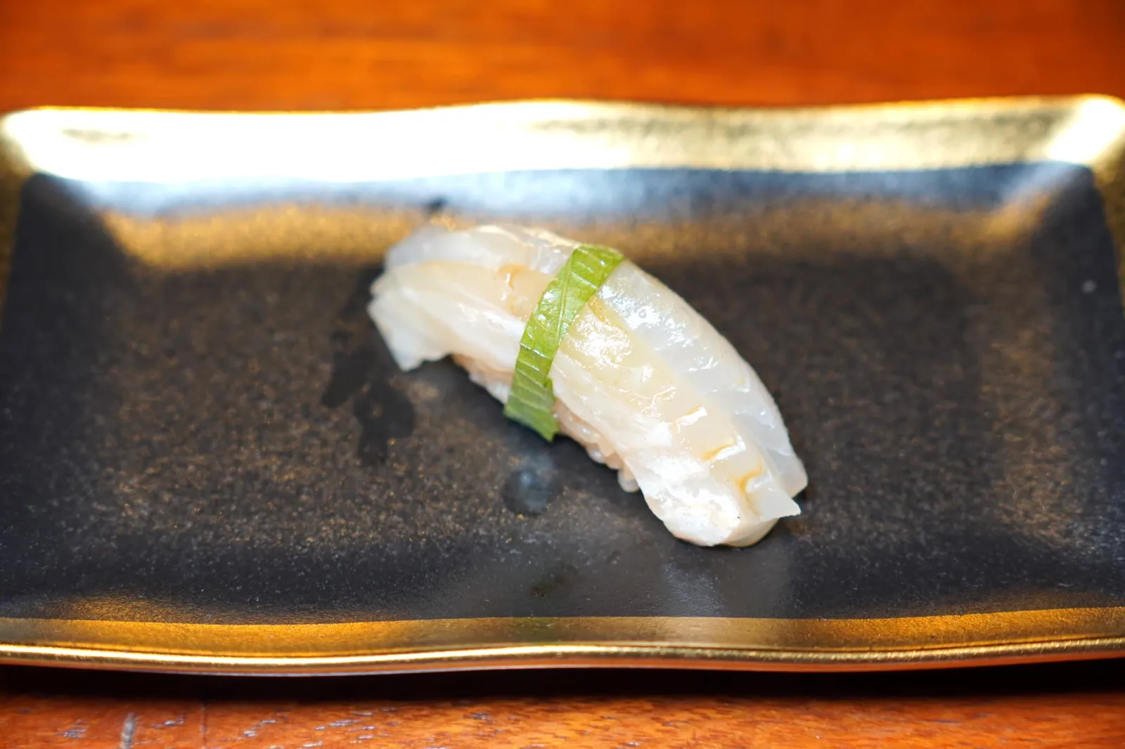 Hirame Nigiri Sushi ฮิราเมะหรือปลาตาเดียวหันซ้ายเป็นปลาตาเดียวชั้นสูงที่มีเนื้อสัมผัสที่ละเอียดอ่อนกว่าคะเรอิหรือปลาตาเดียวหันขวา รอบ ๆ พันล้อมด้วยใบชิโสะให้รสชาติและกลิ่นเฉพาะตัว