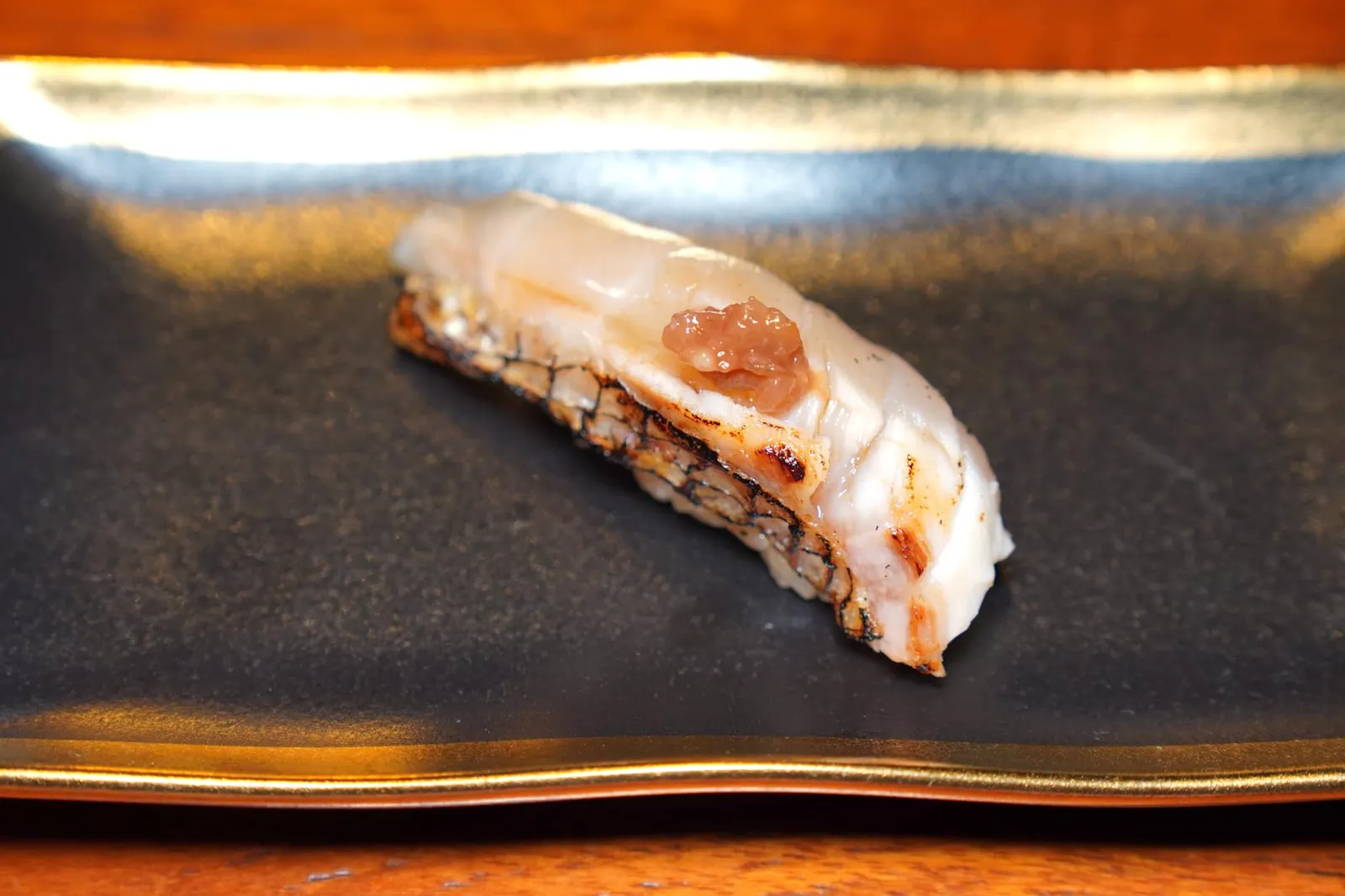 Madai Nigiri Sushi เริ่มต้นนิงิริด้วยมาไดหรือปลากะพงแดงญี่ปุ่น ด้วยความที่เป็นปลาเนื้อขาวทำให้รสชาติของเนื้อปลาอาจยังไม่โดดเด่นนักแต่ทดแทนด้วยเนื้อสัมผัสที่นุ่มหนึบ ทั้งยังมีอัตราส่วนไขมันที่ค่อนข้างสูงเคี้ยวแล้วแทบจะละลายในปากอีกด้วย