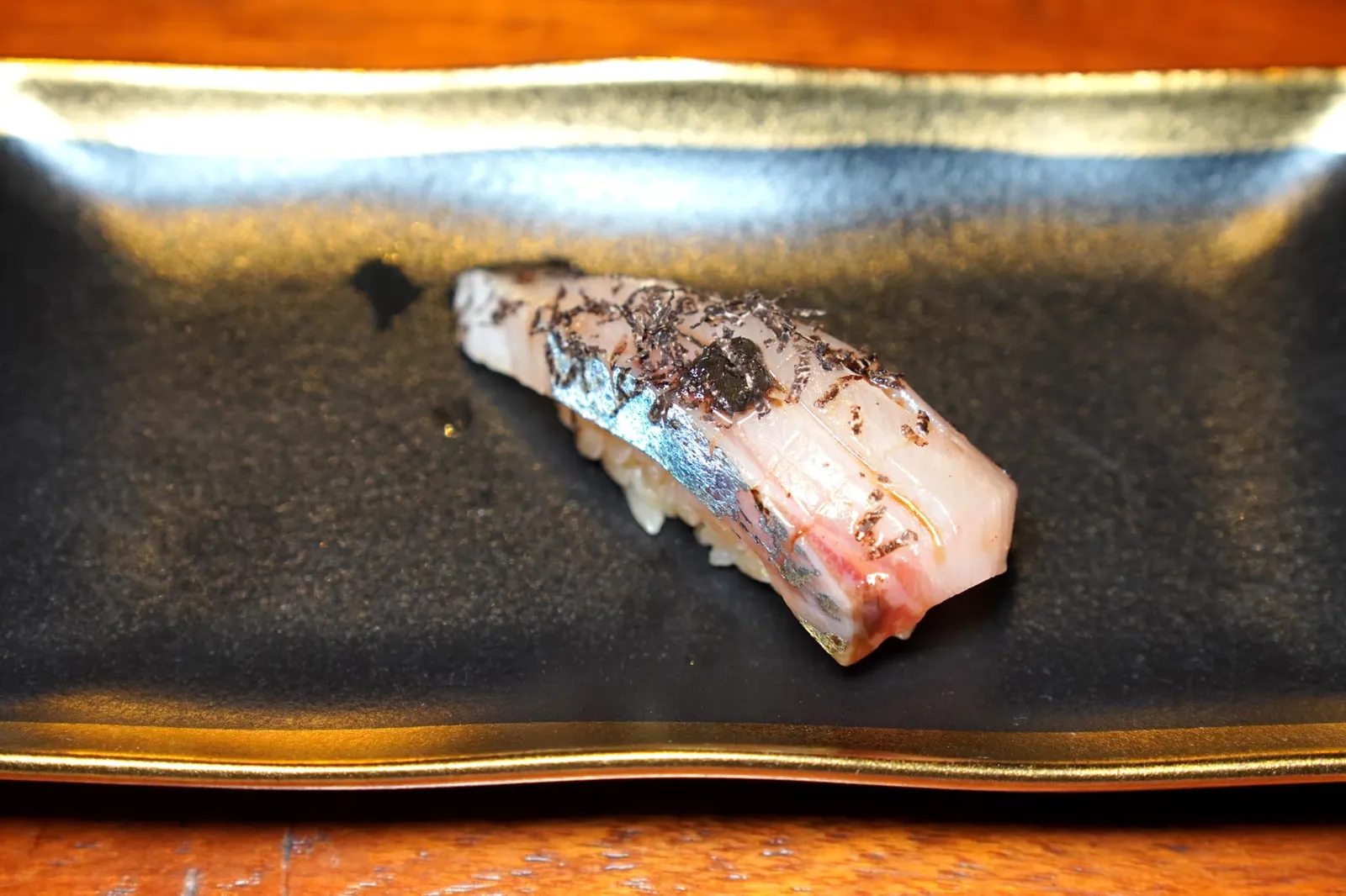 Shima-aji Nigiri Sushi นิงิริปลาชิมะอะจิซึ่งเป็นปลาในกลุ่มปลาทูแขก เ้วยความที่เป็นปลาว่ายทวนน้ำทำให้เนื้อปลามีจุดเด่นที่ความหนึบและรสชาติเค็มอุมามิอันแสนกลมกล่อมบาลานซ์กับความมันของเนื้อปลาได้อย่างพอเหมาะ ด้านบนทอปด้วยทรัฟเฟิลฝนช่วยเสริมกลิ่นเฉพาะตัวของนิงิริคำนี้ให้โดดเด่นมาก ๆ จนกลายมาเป็นคำที่เราประทับใจที่สุดในมื้อนี้เลยก็ว่าได้