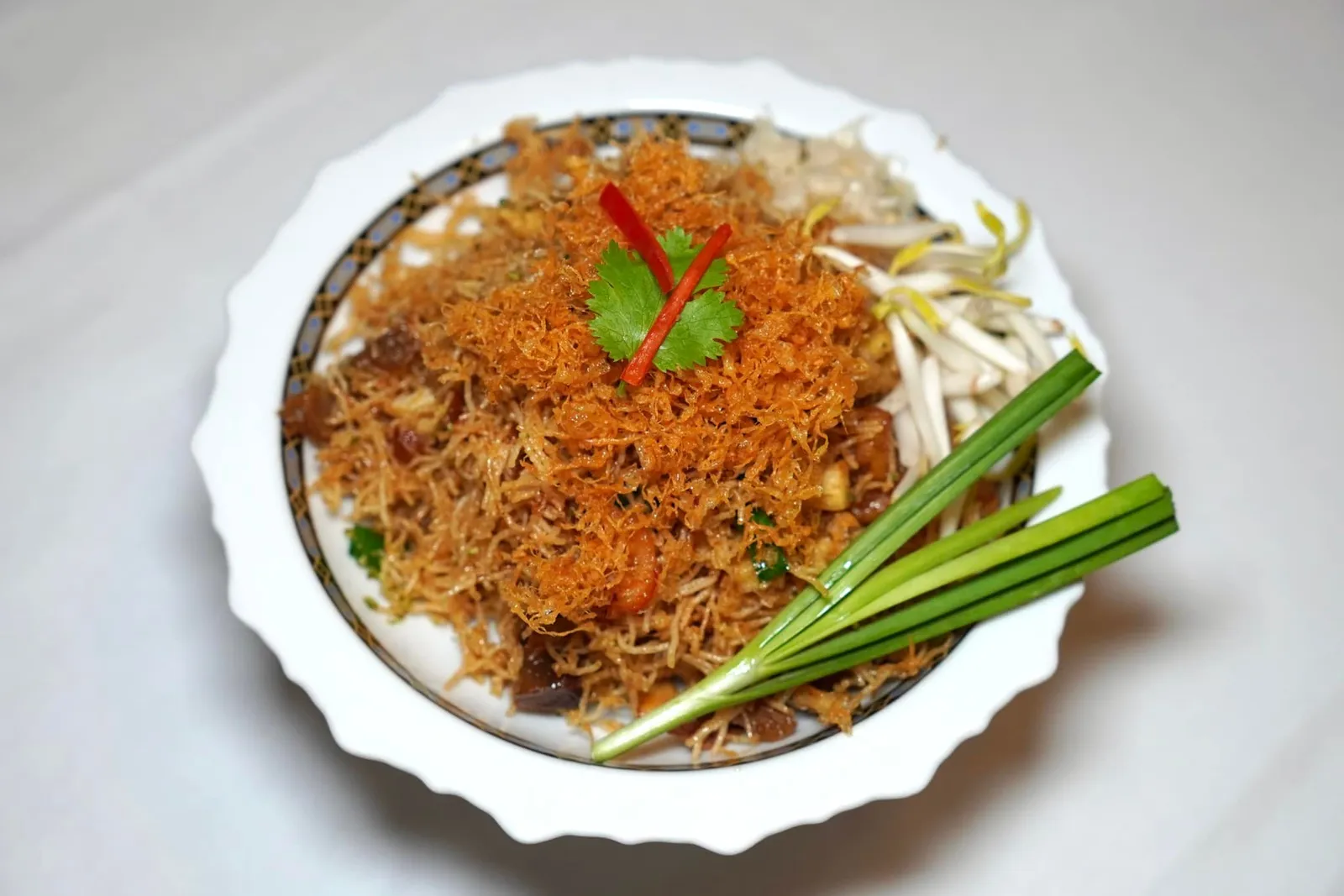 หมี่กรอบชาววัง (150++) Crispy rice noodles in sweet and sour sauce หมี่กรอบชาววังเป็น Signature Dish ที่คงอยู่มาตั้งแต่สมัยร้านศรแดงเดิม เชฟใช้เส้นหมี่ลงทอดจนกรอบไม่อมน้ำมัน ใส่โปรตีนหลักทั้งเนื้อกุ้งและเนื้อหมูให้มิติทางเนื้อสัมผัสแตกต่างกันออกไป ด้านบนทอปด้วยไข่ฝอยฟูเบากรอบและพริกหวานซอย ขนาบข้างด้วยผักเคียงคือถั่วงอก ต้นหอม รับประทานเเล้วจะได้รสหวานจากน้ำตาลปี๊บเข้มข้นที่เคลือบเส้นหมี่ทั่ว ๆ เท่ากันทุกเส้นผสานเข้ากันไปกับรสชาติของส้มซ่าอย่างมีมิติ (14/20)