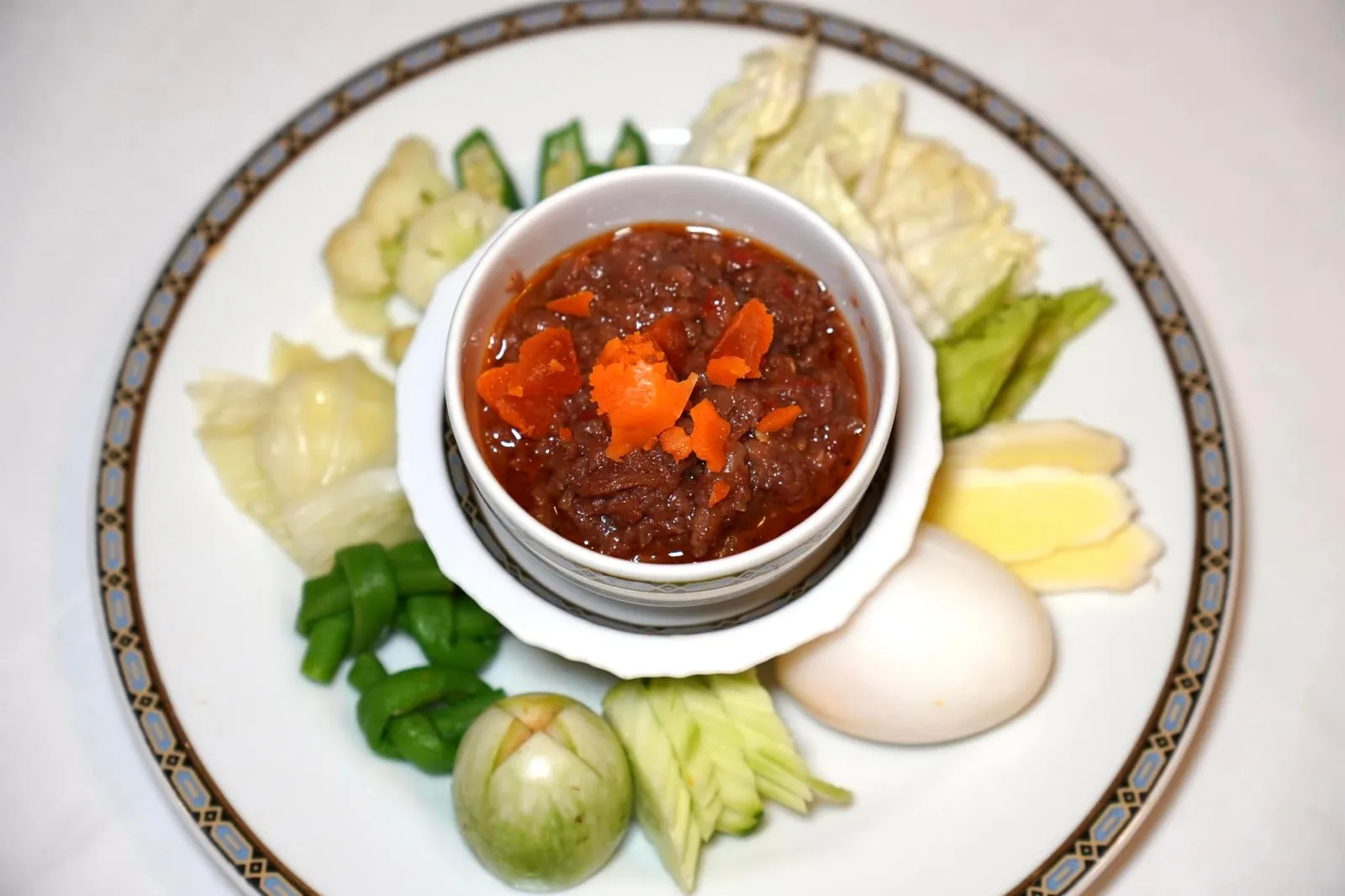 น้ำพริกลงเรือ (210++) Spicy minced pork and shrimp paste dip served with boiled egg and vegetables น้ำพริกลงเรือ เป็นน้ำพริกกะปิตำรับชาววังโดยเจ้าจอมหม่อมราชวงศ์สดับ ในรัชกาลที่ ๕ ปฏิบัติงานในห้องพระเครื่องต้นในราชสำนักที่หม่อมเจ้าสะบาย นิลรัตน์ เป็นหัวหน้าห้องเครื่อง ให้รสชาติเปรี้ยว เค็มทำ แทรกด้วยรสชาติหวานและเผ็ดกลมกล่อม มีความหอมมันของไข่แดงเค็ม รับประทานคู่กันกับผักเคียงหลายชนิด (15/20)