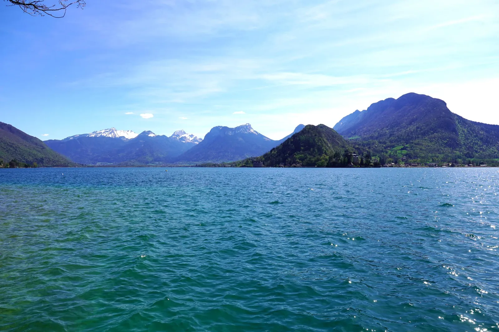 ทะเลสาบสีฟ้าสดใสมีฉากของเทือกเขา The French Alps อยู่เบื้องหลัง