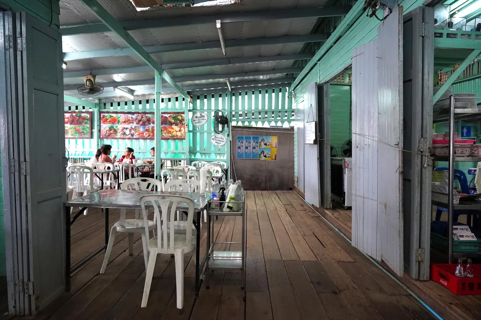 ตัวร้านตั้งอยู่ในย่านปากเกร็ด จังหวัดนนทบุรี มองจากด้านหน้าเป็นบ้านไม้สีเขียวที่มีระเบียงยื่นเข้าไปริมแม่น้ำเจ้าพระยา ปกติลูกค้าจะแย่งกันนั่งริมระเบียงเพื่อชมวิวของสาพานพระราม IV แต่ในวันที่เราไปฝนตกค่อนข้างหนักจนสาดเข้ามาในตัวบ้านเลยต้องเขยิบหนีกันสักหน่อย