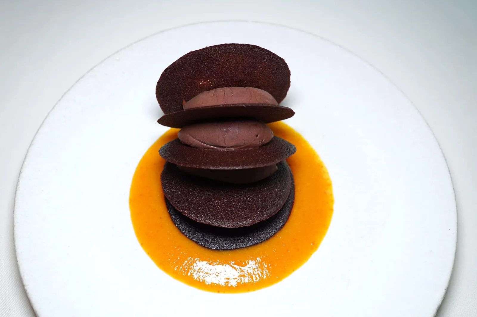Rose des sables à la glace pure chocolat (30 €) coulis d'orange confite สำหรับองค์ประกอบสำคัญ 3 อย่างในจานนี้คือ Cacao Ultra-fines, Bitter Chocolate Sorbet และ Candied Orange Coulis เริ่มจากแผ่น Tuiles กรอบ ๆ ถูกเตรียมจากโกโก้คุณภาพสูง คั่นกลางด้วยซอร์เบท์ช็อกโกแลตเย็น ๆ รสชาติเข้มข้น ความขมของช็อกโกแลตจะบาลานซ์รสชาติกันกับความเปรี้ยวของซอสส้มด้านล่างได้อย่างน่าประทับใจ ถือเป็นเมนูที่เต็มไปด้วยความเรียบง่ายแต่สร้างความซับซ้อนทางรสชาติจากองค์ประกอบหลักเพียง 3 อย่างได้อย่างไร้ที่ติสมกับที่ไม่เคยถูกถอดออกจากรายการเมนูแบบ À La Carte มาจวบจนถึงปัจจุบัน (17/20)