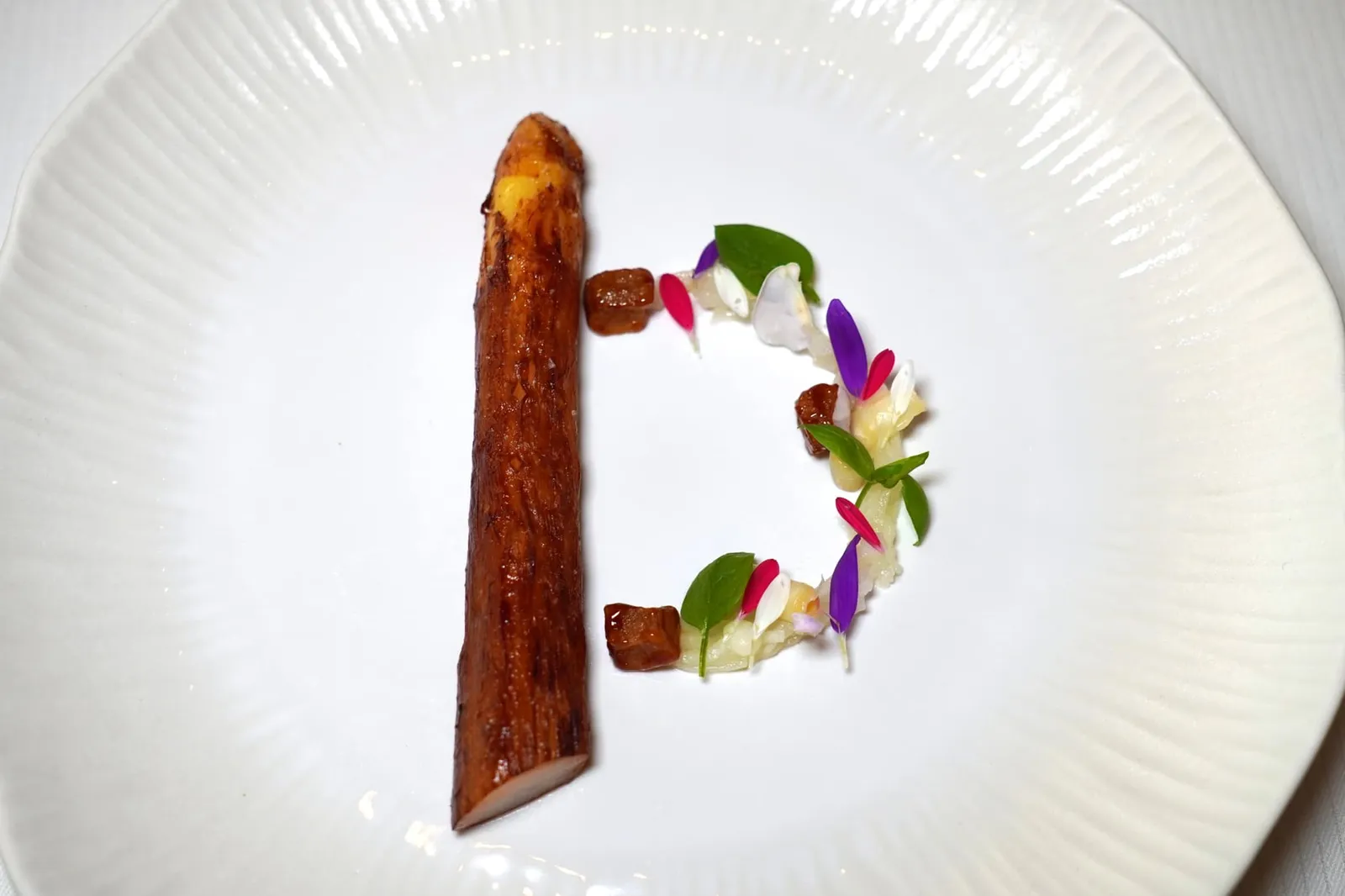 WHITE ASPARAGUS FROM VALAIS Madras curry and bitter orange blossom citron Buddha's hand คอร์สแรกอย่างเป็นทางการคือหน่อไม้ฝรั่งขาวจาก Valais เชฟนำไปหมักกับแกงและ Bitter Orange จากนั้นย่างมาสุกกำลังดีให้ผิวด้านนอกกรอบเล็กน้อยด้านในหวานฉ่ำ องค์ประกอบที่พันอยู่โดยรอบคือ Lardo di Colonnata ส่วนไขมันสัตว์นำเข้าจาก Colonnata เมืองเล็ก ๆ ที่ขึ้นชื่อเรื่องการทำเหมืองหินอ่อน Carrara ทางตะวันตกของประเทศอิตาลี เชฟนำไปผัดกับน้ำผึ้งจนให้ความหวานช่วยบาลานซ์รสชาติเค็มได้อย่างพอเหมาะ (19/20)