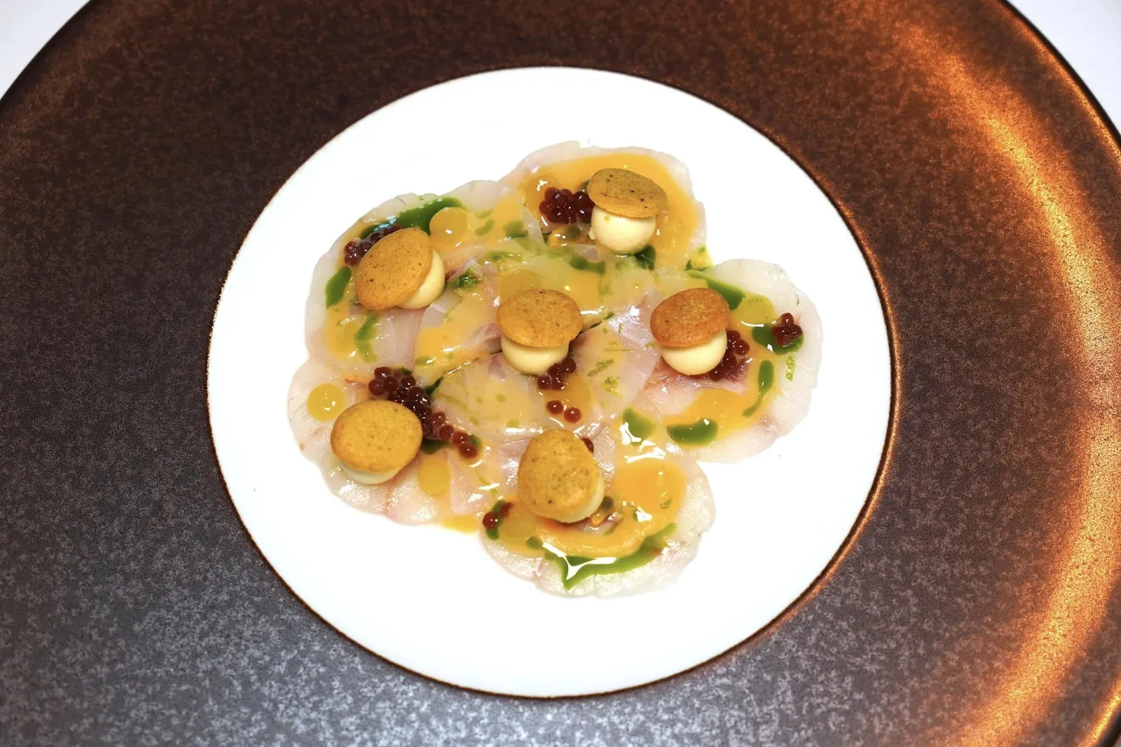 Seabass Ceviche with a cremeux of Colatura di Alici, pearls of anchovies and a passionfruit vinaigrette เริ่มต้นคอร์สแรกอย่างเป็นทางการด้วย Sea Bass หรือปลาในกลุ่มปลากะพงแล่มาเป็นชิ้นบาง ๆ เสริมด้วยรสชาติเค็มอุมามิของ Colatura di Alici หรือน้ำปลาสไตล์อิตาเลียนทำมาจาก Anchovies แล้วเสิร์ฟมาในลักษณะของครีม ด้านบนคือแผ่น Curry Crisp ให้อโรมาหอม ๆ ของแกง รอบ ๆ คือไข่มุกสีน้ำตาลเข้มเตรียมมาจาก Anchovies อีกเช่นกัน จากนั้นเพิ่มความสดชื่นด้วยรสชาติเปรี้ยวของเสาวรสที่ราดมาเป็นซอส Vinaigrette รอบ ๆ จาน (18/20)