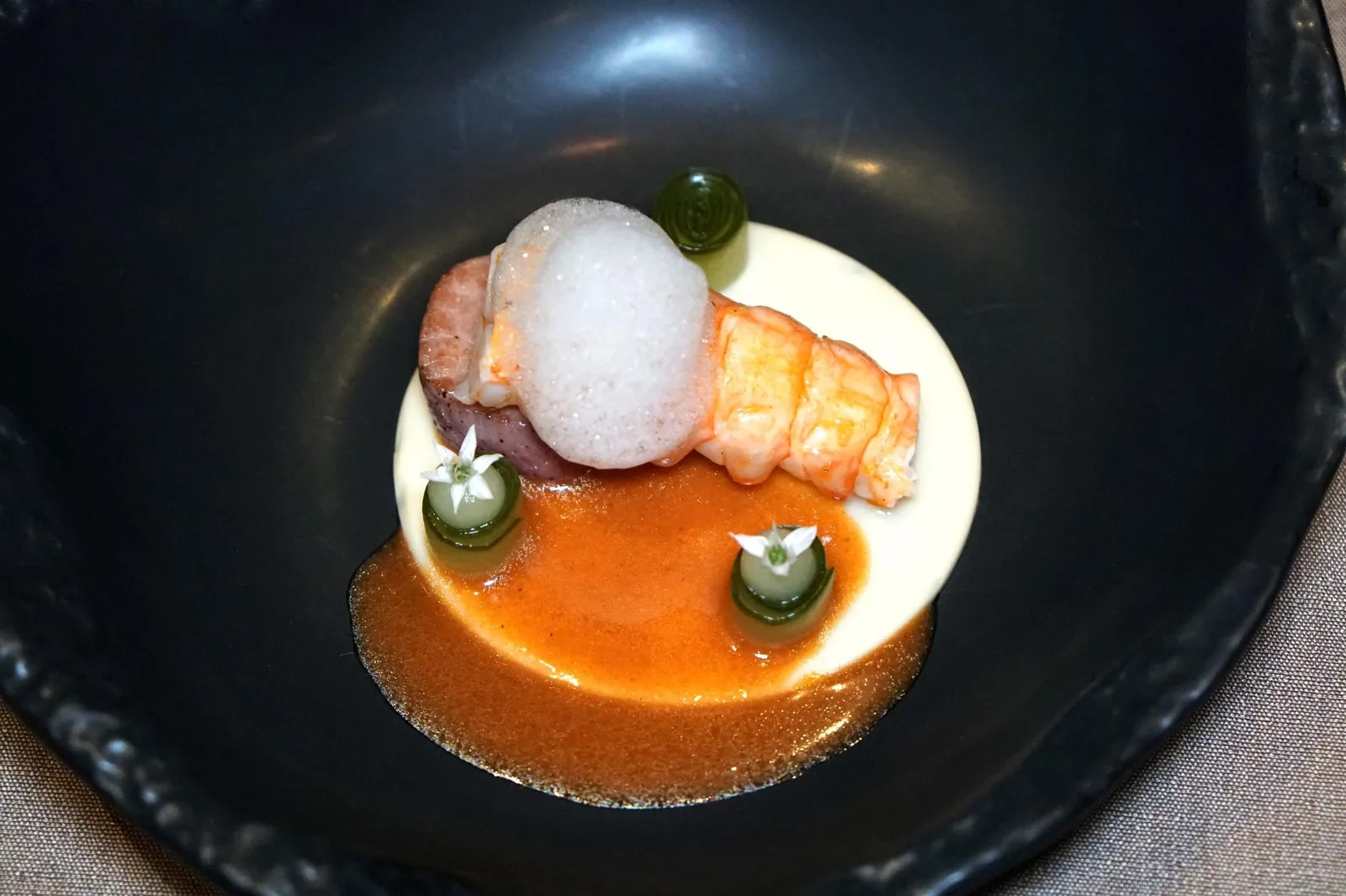 LANGOUSTINE Pork, Celery, Cucumber กุ้ง "แลงกูสทีน" นำเข้าจากแคว้น Brittany ประเทศฝรั่งเศสเนื้อนุ่มหวานดีมากๆ ทอปด้วย Celery foam สีขาวด้านบน ข้างกันคือ Japanese cucumber หรือเเตงกวาญี่ปุ่นเเล่มาบางๆเเล้วพันม้วนมาอย่างสวยงาม จากนั้นหยด Celery gel เอาไว้บนเเตงกวาทานเเล้วให้ความกรอบตัดกันกับความนุ่มของเเลงกูสทีนได้พอดี ด้านล่างคือ Celeriac purée เสิร์ฟมาคู่กับสันคอหมูที่ผ่านการ Slow-cooked จนนุ่ม ก่อนทานพนักงานจะราดซอสสีน้ำตาลส้มที่ได้จากการเคี่ยวส่วนหัวของเเลงกูสทีนลงไปช่วยชูกลิ่นของกุ้งให้เด่นชัดมากยิ่งขึ้น น่าเสียดายที่ตัวซอสใส่มาน้อยไปนิด หากทางร้านวางซอสใส่ภาชนะให้ลูกค้าเติมเพิ่มได้เองน่าจะทำให้ความเป็นเเลงกูสทีนสมบูรณ์เเละเด่นชัดมากยิ่งขึ้น (15/20)