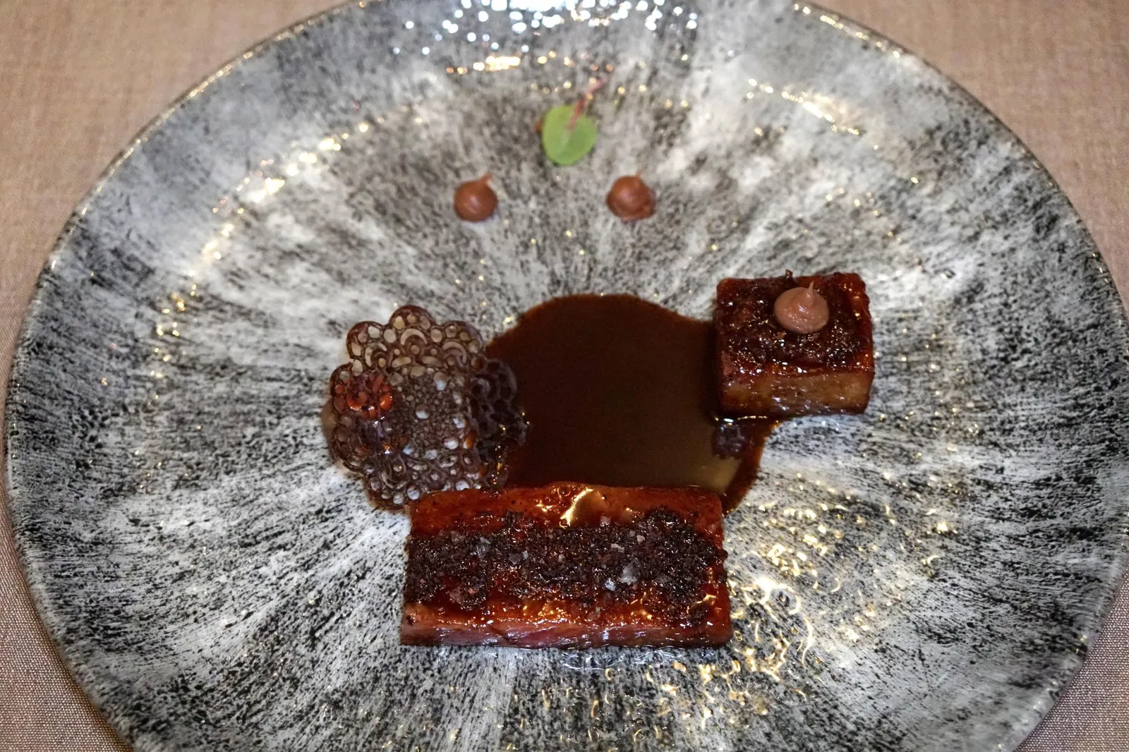 WAGYU BEEF SATSUMA (Supplement of Baht 800 per person) Jagaimo, Nameko เนื้อวัวซัทซึมะวากิวระดับ A5 ส่วน Striploin ที่เชฟนำไป Sous vide ก่อน แล้วจึงนำมาเซียกับกระทะส่งกลิ่นหอมยั่วยวนชวนทานตั้งเเต่ที่พนักงานยกมาเสิร์ฟ เนื้อวัวไขมันเเทรกเยอะมากจนเเทบจะละลายในปากตอนทาน สี่เหลี่ยมฝั่งขวามือคือ Jagaimo หรือ Potato Box เป็นกล่องมันฝรั่งที่เชฟคว้านเนื้อออกไปบางส่วนจากนั้นจึงใส่เนื้อวากิวตุ๋นเอาไว้ด้านใน ตอนทานจะเกิดมิติทางเนื้อสัมผัสที่เเตกต่างขึ้นมา ฝั่งซ้ายมือคือ Champignon Purée เนื้อเนียนทอปด้านบนด้วย Nameko หรือหมวกสีส้มของเห็ดนาเมโกะเละ Black Garlic Tuile หรือแผ่นกรอบทำจากพริกไทยดำ ปิดท้ายด้วยการราด Beef Jus หรือซอสเนื้อที่มีความเข้มข้นค่อนข้างมากเข้าไว้ตรงกลาง ถือเป็นจานที่มีความซับซ้อนทั้งยังมีรสชาติดีงามสมกับเป็นจานเด็ดของมื้อนี้เลยทีเดียว (15/20)