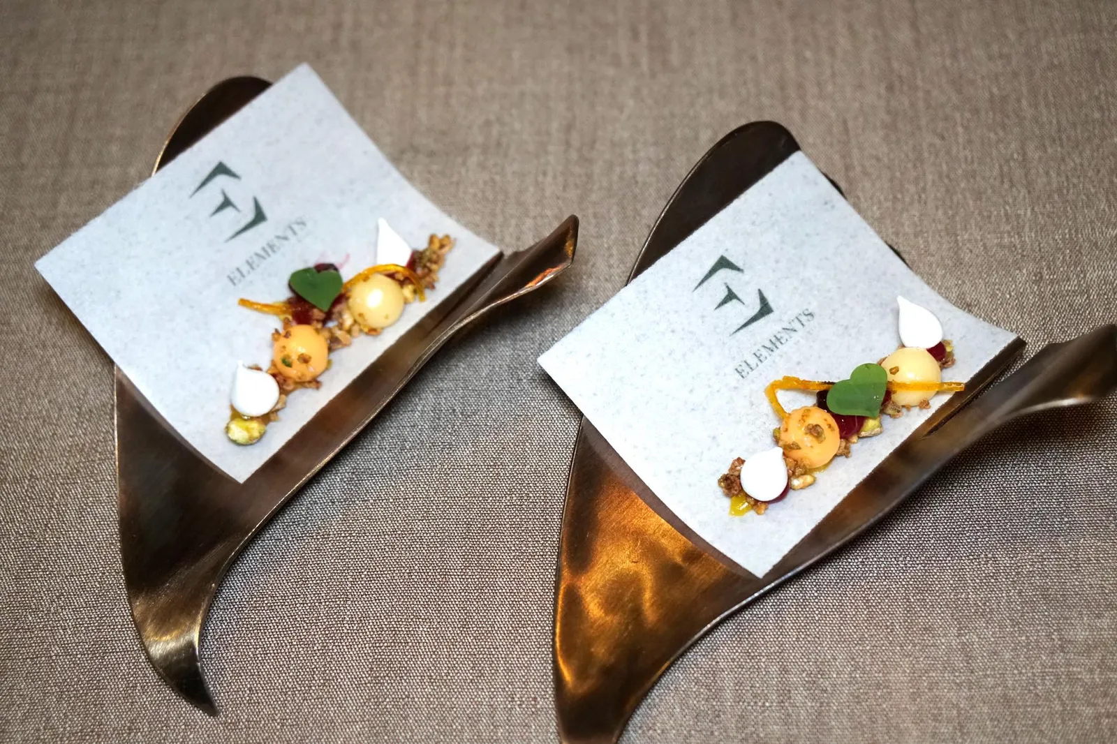 PRE-DESSERT ถัดจากเมนคอร์สพนักงานจะนำเสิร์ฟ Pre-Dessert เพื่อปรับสภาพลิ้นก่อนเข้าสู่คอร์สอาหารหวาน ด้านล่างเป็นซอสทำจาก Yuzu และ Mixed Berries ลูกกลมๆสีส้มสองลูกด้านบนมีสองรสชาติ ฝั่งซ้ายมีสีเข้มกว่าทำมาจาก Blood Orange ส่วนฝั่งขวาที่มีสีอ่อนกว่าทำมาจาก Lemon Grass หรือตะไคร้ ส่วนองค์ประกอบอื่นๆที่ช่วยเพิ่มมิติทางเนื้อสัมผัสมีหลายอย่างคือ Meringe, Dry Berries และถั่ว Pistachio เส้นสีส้มคือผิวส้มหรือ Orange Zest ให้รสขมปลายนิดๆเป็น Aftertaste ทั้งหมดเสิร์ฟมาบนแผ่นกระดาษทานได้สีขาวทำมาจากข้าวญี่ปุ่นพร้อมสลักชื่อร้านมาด้วย ถือว่าทำออกมาได้น่าสนใจ (14/20)