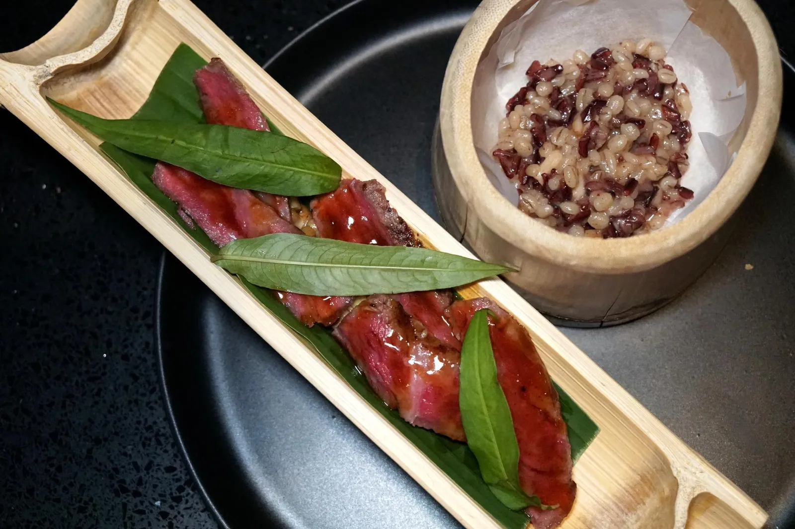 BAMBOO Grilled Iwate Wagyu Beef w/ Seasonal Mushroom, Bamboo Shoot, Koji Sauce, Black Jasmine Rice & Barley Risotto (Additional 400++ THB) สำหรับข้าวในคอร์สเนื้อจะเเตกต่างไปจากคอร์สหมูเล็กน้อยโดยเชฟได้นำข้าวหอมมะลินิลไปผัดกับข้าวบาเลย์เช่นกัน เเต่เชฟเปลี่ยนมาเติมน้ำมันเนื้อและพาเมซานชีสลงไปแทนเพื่อให้ได้รสชาติความเป็นเนื้อที่เข้มข้นกว่าเดิม (14/20)