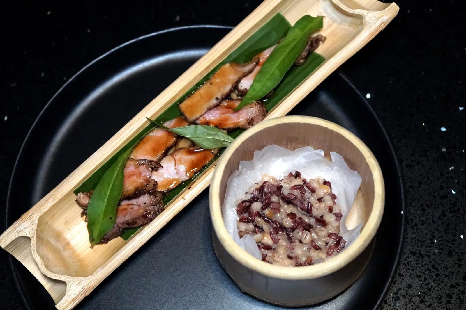 BAMBOO Grilled Pork Collar w/ Seasonal Mushroom, Bamboo Shoot, Koji Sauce, Black Jasmine Rice & Barley Risotto มาถึงเมนคอร์สคือ “ไม้ไผ่” ที่ลูกค้าสามารถเลือกได้ว่าจะทานเป็นสันคอหมูหรือเนื้อวากิว สำหรับหมูทางร้านเลือกใช้ส่วนสันคอหมูคัดพิเศษจากฟาร์มของพนักงานเก่าของทางร้านซึ่งไปเปิดฟาร์มที่จังหวัดราชบุรี เชฟนำไปหมักกับโคจิก่อน จากนั้นจึงนำไปซูวีนานราวๆ 2 ชั่วโมงจนสุก จบด้วยการย่างบนเตาถ่านเพียงชั่วครู่เพื่อให้มีกลิ่นหอมและสีที่สวยงาม ด้านบนราดด้วยซอสดาชิสไตล์ญี่ปุ่น ยังมีผักเเพวซึ่งมีเนื้อสัมผัสเเละกลิ่นที่เป็นเอกลักษณ์ ด้านล่างเป็นเห็ดชิเมจิที่เชฟเเนนนำไปผัดกับหน่อไม้ดองให้เนื้อสัมผัสที่เเตกต่างไปจากเนื้อหมู อร่อยใช้ได้เลยทีเดียว (13/20)