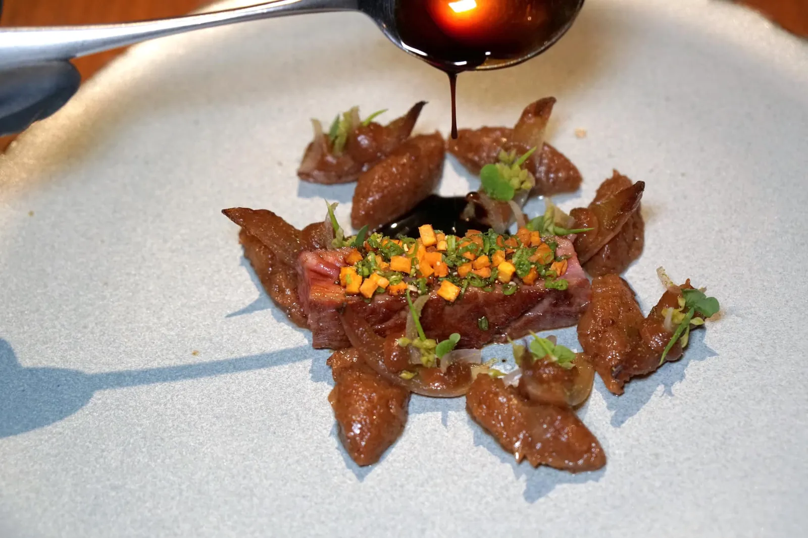 Fifteen years of farming in Nakhon Phanom Wagyu short rib and sweet onion สำหรับเมนคอร์สของเซ็ตเมนู 5 คอร์สคือเนื้อวัวจากจังหวัดนครพนม พนักงานเล่าให้ฟังว่าเมื่อ 15 ปีก่อนเจ้าของฟาร์มได้นำเข้าวัวสายพันธุ์ Japanese Wagyu และสายพันธุ์ Australian มาผสมกันจนได้ลูกผสมออกมาเป็น Thai Wagyu เชฟนำเสิร์ฟมาที่ความสุกระดับ Medium Rare ทอปด้านบนด้วย Crispy Green Onion เเละ Sweet Potato หรือมันหวาน รอบๆคือ Onion in Different Texture หรือหอมใหญ่ในรูปแบบที่แตกต่างกันนั่นเอง ก่อนทานพนักงานจะราด Beef Jus ต่อหน้าลูกค้าบนโต๊ะ (16/20)