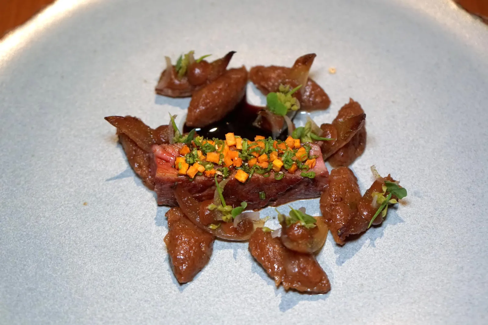 Fifteen years of farming in Nakhon Phanom Wagyu short rib and sweet onion จุดเด่นของเนื้อวัวไทยวากิวคือความนุ่มที่เด่นชัดกว่าเนื้อวัวทั่วไป เเต่ยังมีเนื้อสัมผัสที่ต้องเคี้ยวเเละคงความเป็นเนื้อที่ดีไม่ได้ละลายในปากเหมือนเนื้อวัววากิวเเท้ๆ เหมาะกับการทานคู่กับเครื่องเคียงต่างๆ หอมใหญ่รอบๆเสิร์ฟมาในรูปแบบที่แตกต่างกันให้รสหวานเข้ากันดีกับกลิ่นของเนื้อวัว น้ำซอสรสชาติเข้มข้นชูความเป็นเนื้อให้เด่นชัดออกมามากกว่าเดิม (16/20)