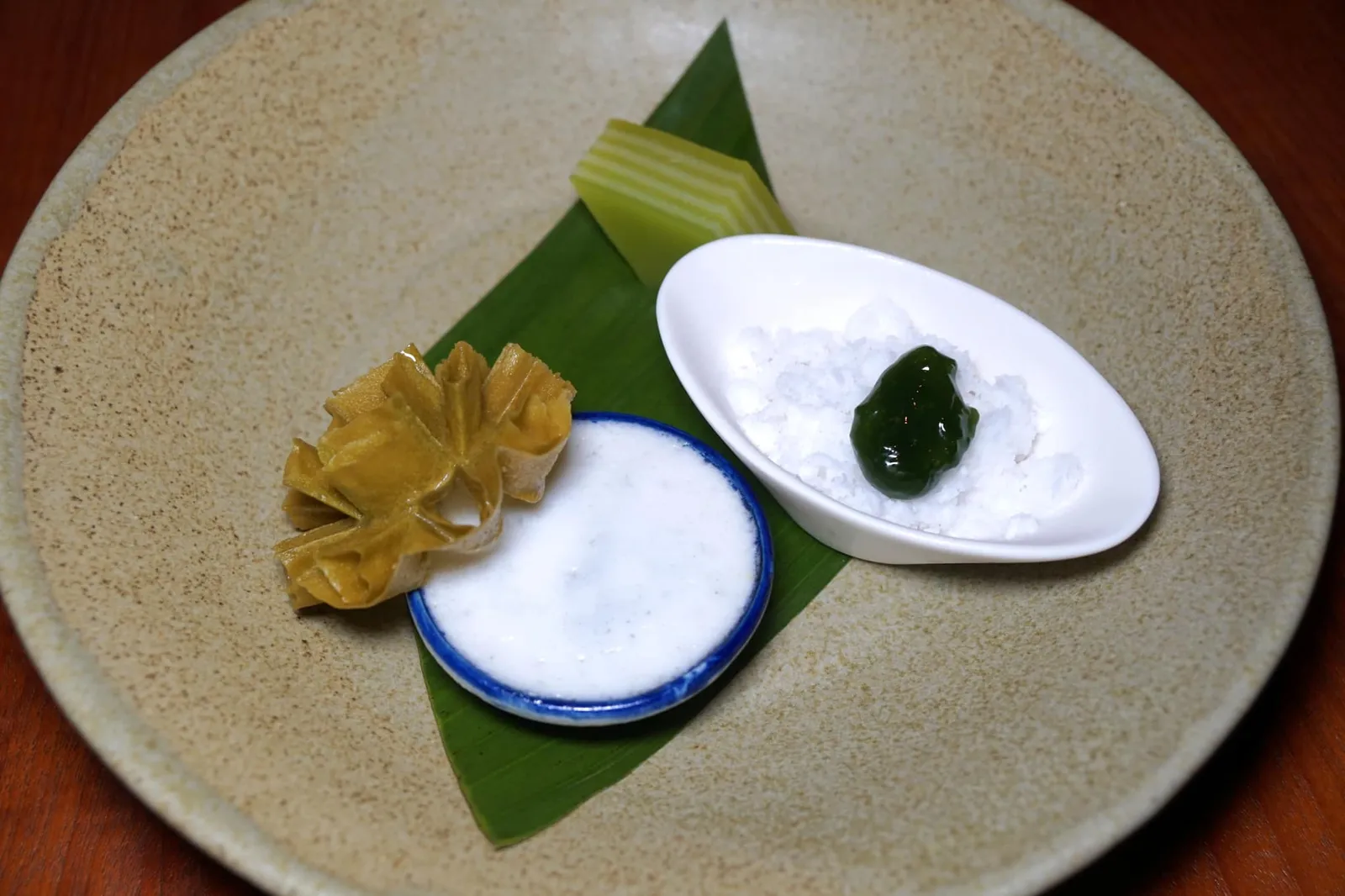 ใบเตย (350++) Textures and flavours of pandan ถัดมาคือ “ใบเตย” ขนมที่นำเสนอเนื้อสัมผัสและรสชาติที่แตกต่างกันขอฝใบเตยซึ่งเป็นวัตถุดิบสำคัญในครัวอาหารหวานของไทย เริ่มจากขนมชั้นใบเตยนุ่มหนึบ มีกลิ่นหอมใบเตยเด่นชัดเจน ถัดมาคืออินทนิล ขนมไทยโบราณที่มีต้นกำเนิดมาตั้งแต่สมัยกรุงศรีอยุธยา แต่เดิมเป็นเมนูที่ทานกันเฉพาะในวังเท่านั้น เชฟพิมทำเนื้อสัมผัสของอินทนิลออกมาได้ไร้ที่ติมากๆ นุ่ม หนึบ หอม เข้ากันดีกับน้ำกะทิด้านล่าง น่าเสียดายมากที่ใส่มาเพียงชิ้นเดียว ในถ้วยกลมคือขนมมันทำมาจากมันสำปะหลัง ตอนทานจะได้ความหนึบและสู้ฟันมากกว่าขนมถ้วยที่เราคุ้นเคยกัน สุดท้ายคือขนมดอกจอกใบเตย ทั้งกรอบ หอม และอร่อยไม่เบา (15/20)