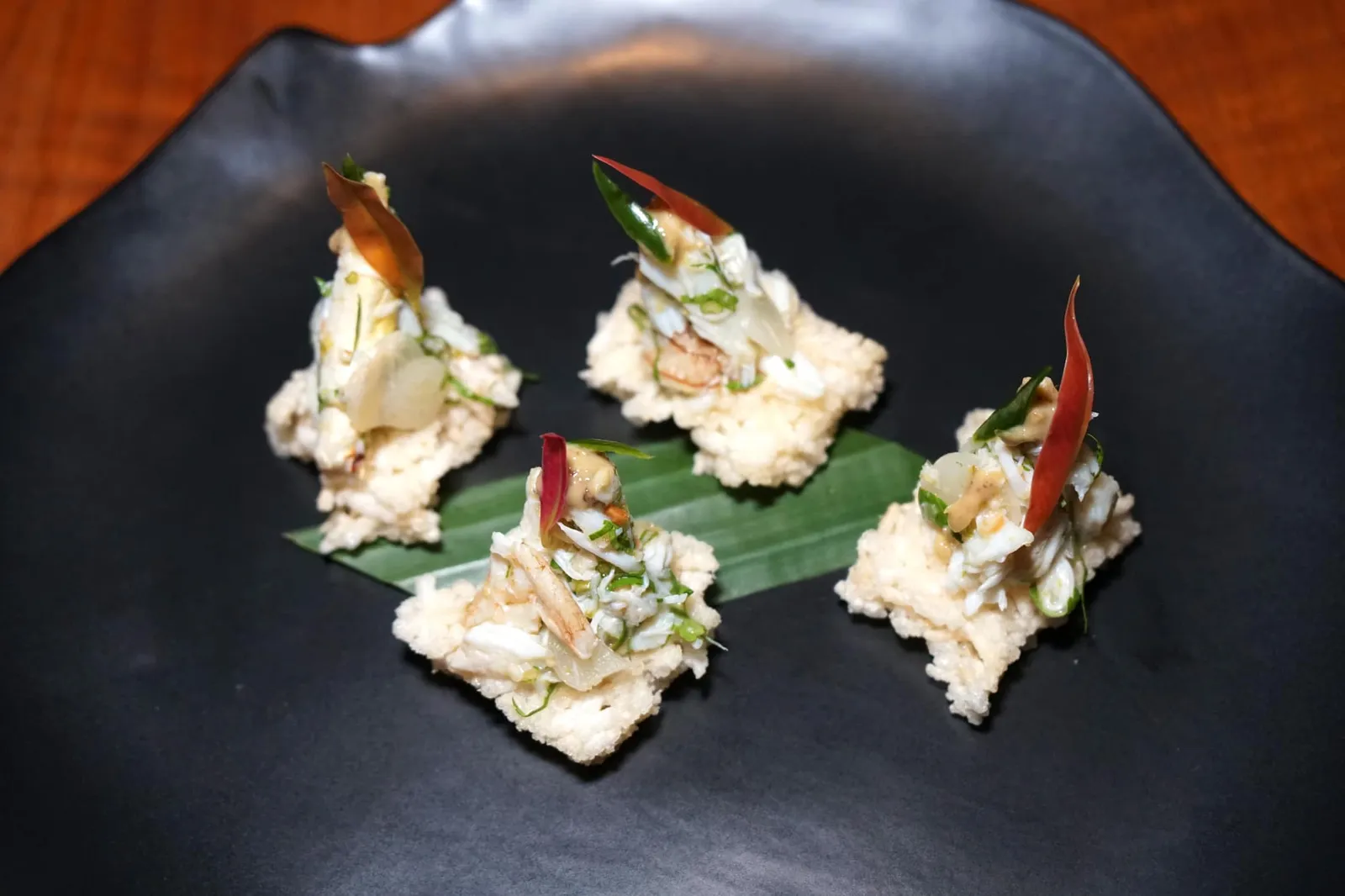 ปูซ่อนกลิ่น (460++) Blue swimmer crab, coriander and pickled garlic on rice crackers with peanuts เริ่มต้นมื้ออาหารด้วยอาหารเรียกน้ำย่อยอย่าง “ปูซ่อนกลิ่น” ที่ได้จากการนำเนื้อปูม้าสดๆมาคลุกกับพริกขี้หนูสวน ถั่วลิสง และกระเทียมดอง ด้านล่างเป็นข้าวตังกรอบเพิ่มมิติทางเนื้อสัมผัส ด้านบนราดด้วยน้ำเดรสซิ่งที่ได้จากการผสมน้ำส้มซ่า น้ำมะนาว น้ำตาลปี๊บ น้ำปลาชั้นดี และรากผักชีลงไปเพื่อเพิ่มความเป็นซิตรัสช่วยชูรสหวานของเนื้อปูให้เด่นชัดมากยิ่งขึ้น ทอปด้วยใบชะมวงและพริกเขียว นอกจากรสชาติที่อร่อยแล้วยังจัดเป็นจานที่กระตุ้นความอยากอาหารก่อนเข้าสู่อาหารจานหลักได้เป็นอย่างดี (14/20)
