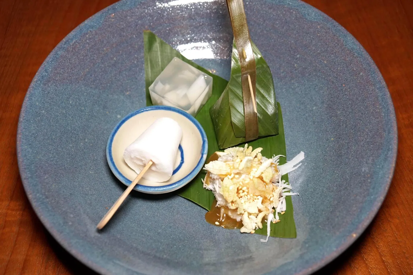 มะพร้าว (350++) Life cycle of coconut เริ่มจาก “มะพร้าว” ขนมหวาน 4 อย่างที่เชฟพิมตั้งใจนำเสนอวัตถุดิบหลักชนิดเดียวแต่แตกต่างกันที่ช่วงเวลาการเก็บเกี่ยว อย่างแรกคือ “ไอติมมะพร้าว” โบราณที่ได้จากการปั่นผสมน้ำและเนื้อมะพร้าวรวมกัน หอม สดชื่นมากๆ ถัดมาคือ “ขนมเหนียว” เคี้ยวหนึบทำมาจากแป้งข้าวเหนียว ด้านบนโรยด้วยมะพร้าวขูดและน้ำไซรัปจากดอกมะพร้าวทั้งหอมทั้งหวานกลมกล่อม เพิ่มมิติทางเนื้อสัมผัสด้วยการโรยข้าวตอกและงาขาวลงไปด้วย ชิ้นขวาบนคือ “ขนมใส่ไส้” ทำมาจากมะพร้าวเช่นกัน เนื้อสัมผัสนุ่ม ละมุนลิ้น ไส้ด้านในเค็มนิดๆพอประมาณ ปิดท้ายด้วย “วุ้นมะพร้าว” ชั้นดีที่ได้จากการนำเนื้อมะพร้าวไปขึ้นรูป ด้านในมีเนื้อมะพร้าวใส่อยู่ด้วย (15/20)