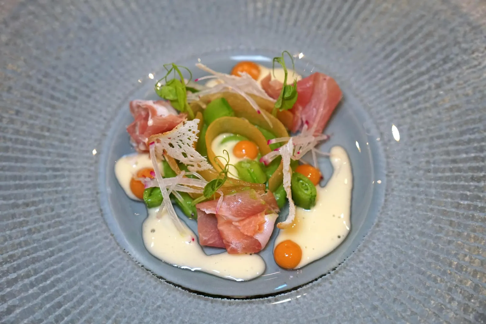 ENGLISH PEA melon | proscuitto | lemon “ถั่ว” เสิร์ฟมาตรงกลางในรูปแบบพูเรคู่กับยอดอ่อน เพิ่มความกรอบด้วย Snow pea ที่เชฟหั่นเป็นชิ้นวางมารอบ ๆ จาน คู่กับเลมอนเจลสีเหลืองกระจายอยู่รอบ ๆ ส่วนพระรองของจานคือ Proscuitto อายุ 16 เดือนนำเข้าจากประเทศอิตาลีให้เนื้อสัมผัสที่นุ่มหนึบ ชิ้นบาง ๆ ตรงกลางคือ Compressed melon ที่เชฟบีบอัดกับน้ำเมลอนอีกทีจนได้เป็นแผ่นบาง ๆ รสชาติเข้มข้น จบด้วยการราดซอส Melon vinaigrette สีครีมลงไปรอบ ๆ จาน (15/20)