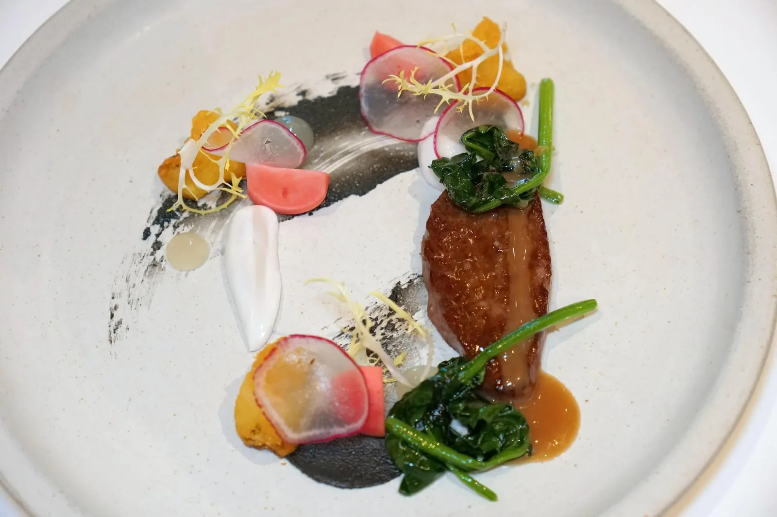 KAGOSHIMA WAGYU coconut | black sesame | yuzu จานนี้เชฟแดนได้เนื้อวัว “คาโกชิมะ วากิว” มาจากประเทศญี่ปุ่นเสิร์ฟมาที่ความสุกระดับมีเดียมแรร์พร้อมกับ Yuzu vinaigrette และ Yuzu purée ให้รสชาติออกเปรี้ยวตัดด้วยความหวานและกลิ่นจากการรมควันของของ Smoked coconut purée ส่วนผักเคียงมีหลายชนิดเริ่มจากผักโขมที่เชฟ Sauteed ในน้ำมันกระเทียมจนหอมและนุ่ม ยังมีแรดิชเสิร์ฟมาทั้งแบบสดและดอง ส่วน Mashed potato เชฟ Dan ทำออกมาให้มีความกรอบเพื่อให้ตัดกันกับความนุ่มละมุนของเนื้อวากิวนั่นเอง (15/20)