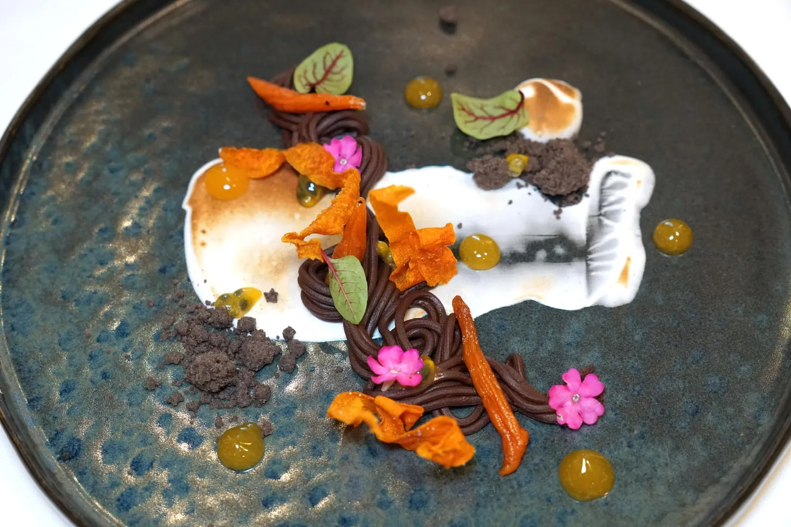 DARK CHOCOLATE carrot | cardamom | passion fruit จานนี้คือ “ดาร์คช็อกโกแลต” 72% ทำออกมาเป็นกานาชเสิร์ฟมาคู่กับช็อกโกแลตครัมเบิ้ลกรอบข้างกัน สีขาวด้านล่างคือเมอแรงก์ที่มีส่วนผสมของกระวานมีรสหวานและกลิ่นเฉพาะตัวเข้ากันดีกับกลิ่นของช็อกโกแลต ยังมีแครอทที่ทำเป็น Chips กรอบ ๆ และแครอทที่ Candied แล้วอบจนนุ่มและมีรสหวาน เจลสีเหลืองทำมาจากเสาวรสให้รสเปรี้ยว หากสังเกตดี ๆ จะพบกับเมล็ดเสาวรส, ผิวมะนาว ใบ Red veined sorrel และดอก Lemon verbena สีชมพูใส่มาด้วย (15/20)