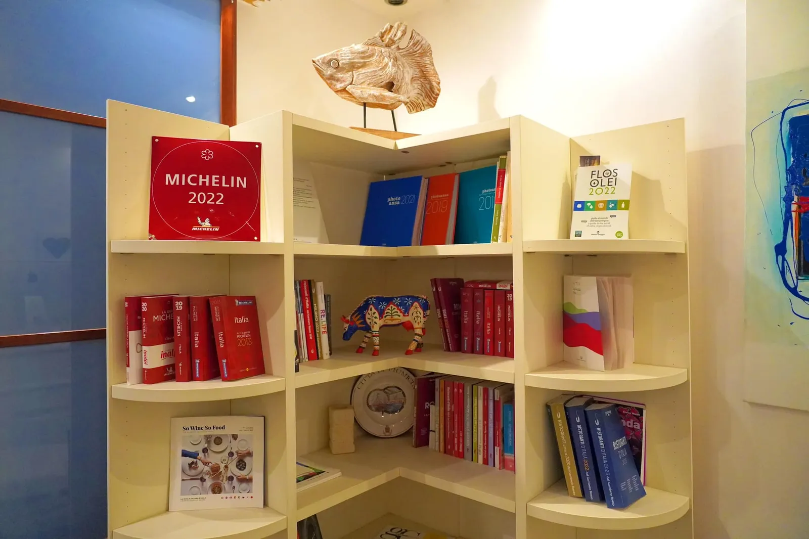 พื้นที่ด้านหน้าถูกเตรียมไว้สำหรับตรวจสอบการจองและรองรับลูกค้าโดยมีโล่ MICHELIN Star และคู่มือปกแดงจำนวนมากวางเรียงรายกันอยู่บนชั้น