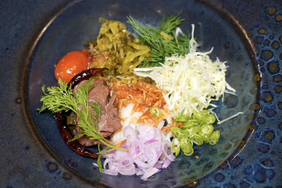 🥄 PRE-MAIN COURSE อ่อมงัวข้าวปุ้น Rice noodle with Isaan beef curry broth อ่อมงัวข้าวปุ้นเป็นเมนูที่ได้จากการนำเนื้อแก้มวัวไปตุ๋นในน้ำแกงเพื่อให้ได้รสชาติที่เข้มข้น จากนั้นใส่น้ำปลาร้าลงไปเพื่อให้มีกลิ่นหอมเฉพาะตัว ในน้ำแกงยังมีปลาแห้งตำและผักชีลาวอยู่ด้วย (15/20)