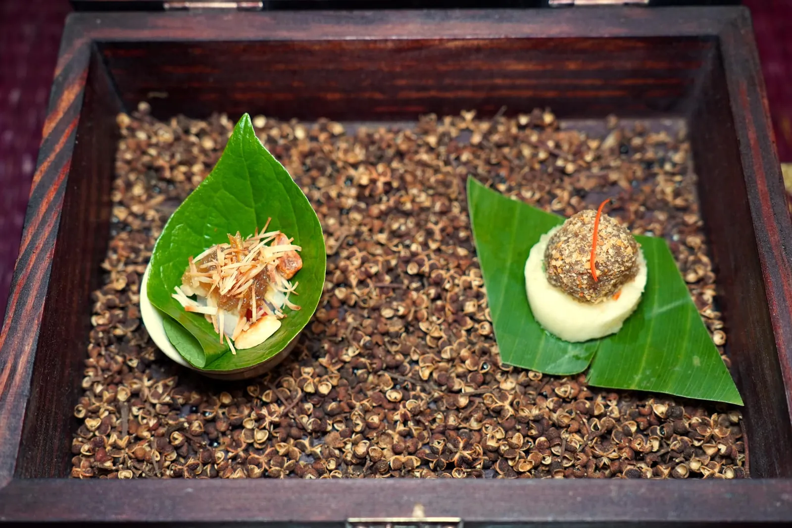 🥄 AMUSE BOUCHE หลนปู เมี่ยงคำหลวง ม้าฮ่อ Amuse bouche of the day คำที่สองคือเมี่ยงคำหลวงที่เชฟใส่ปลาป่นกรอบ ๆ ลงไปด้วยช่วยเพิ่มมิติทางเนื้อสัมผัสให้ตัดกันกับใบชะพลู เชฟเตรียมน้ำเมี่ยงคำโดยใช้วิธีแบบดั้งเดิมคือการใส่ข่า น้ำตาลมะพร้าว และน้ำมะพร้าวเคี่ยวจนข้นเพื่อให้ได้รสชาติที่หวานกลมกล่อม สุดท้ายคือ “ม้าฮ่อ” องค์ประกอบด้านล่างคือสับปะรดที่นำไปผ่านกระบวนการ Compressed ให้ดูดน้ำสับปะรดกลับเข้าไปจนได้เนื้อสัมผัสที่ฉ่ำและคงความกรอบเอาไว้ได้เป็นอย่างดี ด้านบนคือองค์ประกอบที่ได้จากการนำถั่วและหัวไชโป๊หวานไปเคี่ยวกับน้ำตาลโตนดจนข้น จากนั้นปั้นเป็นก้อนกล แล้วนำมาคลุกกับถั่วบดอีกทีหนึ่ง (15/20)