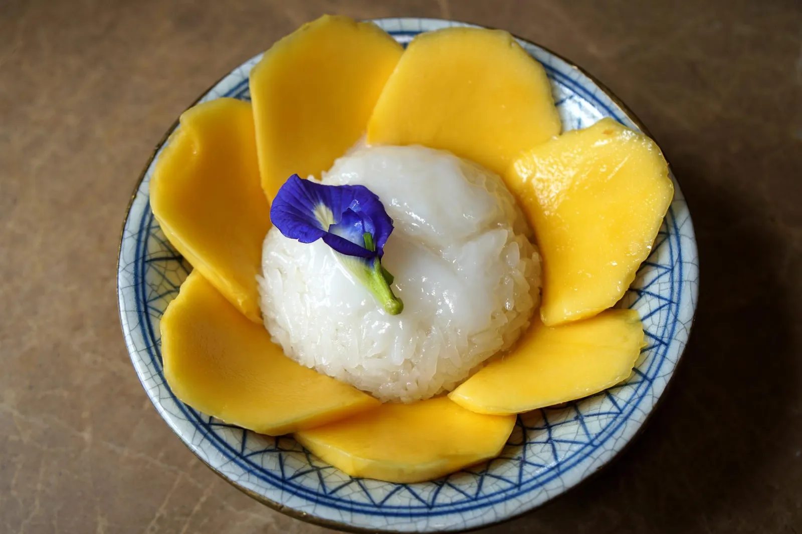 ข้าวเหนียวมะม่วง Sticky rice with fresh mango ด้วยความที่บ้านหลังนี้เป็นบ้านกลางจึงมีลูกหลานมาเยี่ยมเยือนรวมถึงฝากเลี้ยงกันเป็นประจำ ในช่วงปิดเทอมซึ่งเป็นหน้าที่มะม่วงมีรสชาติอร่อยที่สุด คุณยายมักทำข้าวเหนียวมะม่วงเมนูโปรดของเด็กๆมาแบ่งให้ทานกัน ข้าวเหนียวคุณภาพที่นำไปมูนกับหัวกะทิจนมีความมัน หอม ราดด้วยน้ำกะทิข้นกำลังเเละถั่วเหลืองกรอบ ทานกับมะม่วงสุกรสหวานอร่อย ปิดท้ายมื้ออาหารได้อย่างน่าประทับใจ (12/20)