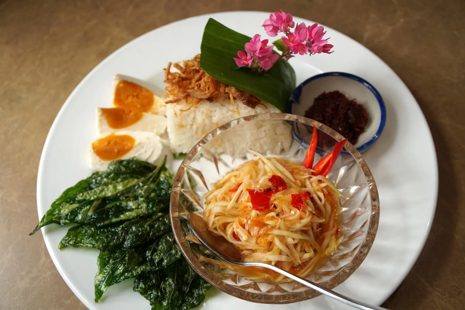 ข้าวมันส้มตำ Khao Man Som Tam ทางร้านใช้ข้าวมันนำไปหุงกับกะทิด้วยเตาถ่านจนหอม เนื้อสัมผัสของเมล็ดข้าวนุ่มมันพอดีมากๆ ทอปด้านบนด้วยหมูฝอยให้รสชาติหวานนำห่อมาในใบตองดูสวยงามน่าทาน ทานกับส้มตำไทยรสชาติจัดจ้าน ครบทั้งเปรี้ยวหวานเค็มและเผ็ดนิดๆ ข้างกันคือไข่เค็มตัดรสหวาน มีน้ำพริกแดงที่ใช้พริกแดงตำกับมะขามเปียกให้รสเปรี้ยวนิดๆ สุดท้ายที่ขาดไม่ได้คือผักทอดอย่างใบทองหลางหรือใบชะพลูและผักแนม (14/20)