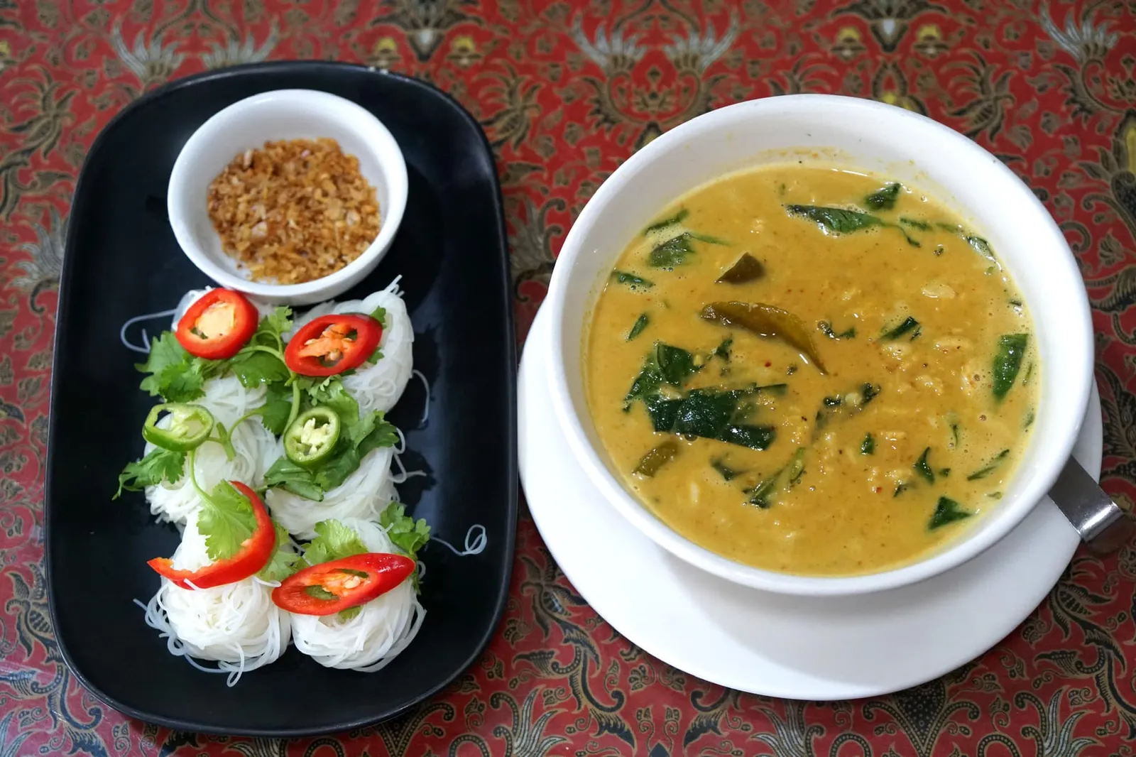 หมี่หุ้นแกงปู (190) Crab meat coconut milk curry soup with rice noodle แกงปูใบชะพลูเป็นอาหารพื้นเมืองของชาวภูเก็ต ด้วยความที่มีวัตถุดิบจากท้องทะเลมากคนท้องถิ่นจึงเลือกใช้เนื้อปูมาสับเเล้วเทใส่ลงไป น้ำแกงเข้มข้น มีสีเหลืองสวย ดูน่าทาน เสิร์ฟมากับหมี่หุ้นตามแบบพื้นเมืองภูเก็ต (13/20)