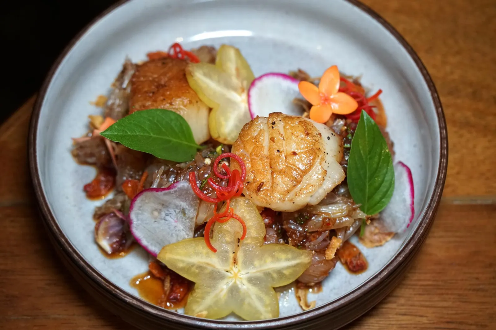 ยำส้มโอและหอยเชลล์จัมโบ้ย่าง (349++) Pomelo salad with grilled sea scallops, Thai basil and crispy dried shrimp อีกหนึ่งจานเด็ดในวันนี้ที่ทำรสชาติออกมาได้น่าประทับใจคือเมนู "ยำส้มโอ" เชฟใช้ส้มโอไปคลุกเคล้ากับน้ำพริกเผาชั้นดี ความหวานของส้มโอถูกเสริมด้วยความมันเบาๆและรสเผ็ดเพียงเล็กน้อยของน้ำพริกจนเกิดเป็นมิติทางรสชาติ เชฟเพิ่มความกรอบด้วยการใส่กุ้งเสียบซึ่งเป็นวัตถุดิบท้องถิ่นของเมืองภูเก็ตลงไปด้วย เสิร์ฟให้ทานกับ Great scallops หรือหอยเชลล์ยักษ์นำเข้าจากประเทศอเมริกา ตัวหอยเชลล์ถูกจี่มาในความร้อนเเละเวลาที่พอเหมาะทำให้เนื้อด้านในนุ่ม หวาน เสิร์ฟมาพออุ่นๆ ด้วยความที่วัตถุดิบหลักของจานเสิร์ฟในอุณหภูมิที่แตกต่างกันเราจึงขอเเนะนำให้ทานยำส้มโอที่เสิร์ฟมาเย็นๆสลับกันกับหอยเชลล์ที่เสิร์ฟมาอุ่นๆจะอร่อยมาก (14/20)