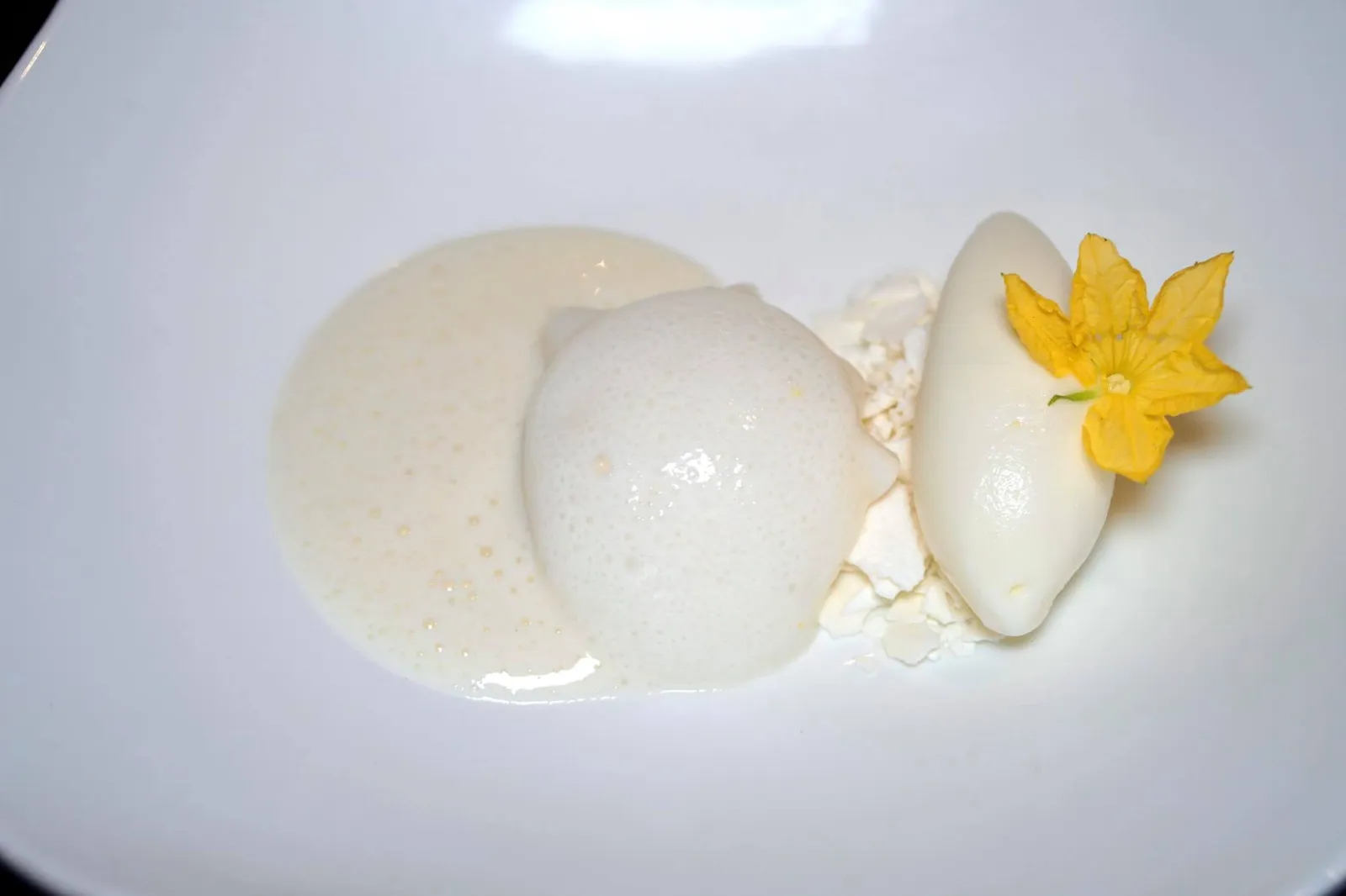 Memories of “Fior di Latte” Milk semifreddo, foam, gelatin, sauce and gelato ปิดท้ายด้วยอาหารหวาน เเละยังเป็นจานที่ดีที่สุดในมื้อนี้เรียกว่า “ความทรงจำของฟิยอ ดิ ลัตเต้” เเน่นอนว่าองค์ประกอบหลักของจานคือ Fior di Latte หรือไอศกรีมเจลาโต้แบบที่ไม่ได้ใส่รสชาติเสริมลงไปนั่นเอง เชฟเล่าให้เราฟังว่าจานนี้ได้รับเเรงบันดาลใจมาจากความทรงจำในวัยเด็กเมื่อคุณเเม่พาเขาไปที่ร้านกาแฟเพื่อซื้อไอศกรีม สำหรับเด็กๆถือเป็นเรื่องใหญ่ที่น่าตื่นเต้นมากๆ เชฟได้นำ Fior di Latte เสิร์ฟมาในรูปแบบ Different textures เริ่มจาก 1) เซมิเฟรดโด้ทรงกลม 2) คลุมด้วยแผ่นเจลาติน 3) โรยหน้าด้วยโฟมด้านบน 4) ข้างกันฝั่งขวาคือซอส 5) ส่วนฝั่งซ้ายคือเจลาโต้ สำหรับซอสเเละโฟมเชฟใส่ผิวเลมอนลงไปเล็กนิดเพื่อเพิ่ม acidity flavor เพียงเล็กน้อย แผ่นตรงกลางคือเมอแรงก์ที่เสริมความกรอบเเละรสหวานนิดๆให้กับจาน ความสุดยอดของจานนี้คือการที่เชฟนำ Fior di Latte มาทำเป็นองค์ประกอบที่เเตกต่างกัน ทุกอย่างมีกลิ่นหอมนม มีเนื้อสัมผัสที่หลากหลาย รสชาติหวานกำลังดี อร่อยเลิศ ทั้งยังเป็นการสื่อความทรงจำในวัยเด็กของตัวเชฟเองผ่านอาหารเพียงหนึ่งจานออกมาได้อย่างไร้ที่ติจนเรายอยกให้เป็นหนึ่งในอาหารจานที่ดีที่สุดในทริปภูเก็ตนี้เลยทีเดียว (17/20)