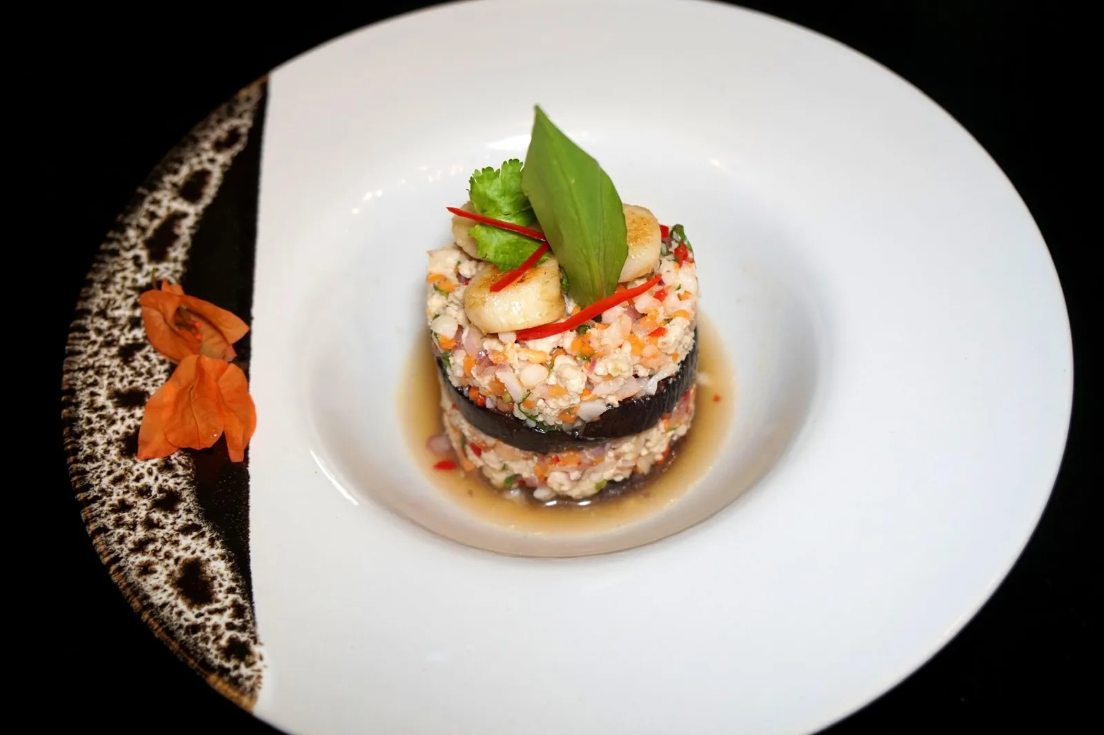 ยำมะเขือม่วงโครงการณ์หลวงหอยเชลล์ (480++) ROYAL POJECT EGGPLANT Inspired by her collaboration with the Royal Project Vegetables and Herbs Farm, Purple Eggplant Salad with Grilled Scallops - Free Range Chicken - Andaman deep Sea Tiger Prawn, Herbal Spiciness and a hint of Truffle อาหารจานถัดมาคือยำมะเขือม่วง ทางร้านเลือกใช้มะเขือม่วงชิ้นโตจากโครงการณ์หลวงนำไปนึ่งจนสุกกำลังดี เนื้อสัมผัสนุ่ม ไม่เละ ไม่มีกลิ่นดินหรือ Earthy aroma ปนมารบกวนแม้แต่น้อย เชฟนำไปยำกับกุ้งสับ, ไก่สับ และหอยเชลล์ไทย มีรสเปรี้ยวหวานพอเหมาะ มีรสเผ็ดเบาๆ สุดท้ายจุดที่เรารู้สึกประทับใจมากๆคืออโรม่าของเห็ดทรัฟเฟิลที่จะไม่ได้โดดเด่นในตอนเเรกที่ตักเข้าปาก แต่จะเริ่มชัดขึ้นมาหลังกลืนอาหารลงไปแล้วสักพักเพื่อเลี่ยงการปะทะกันของกลิ่นน้ำยำเเละกลิ่นของทรัฟเฟิล (14/20)