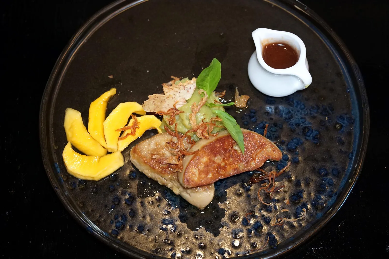 ตับห่านซอสมะขาม (780++) THAI TAMARIND & FRENCH “LANDES” FOIE GRAS Ambassador of Rougier, Chef Nooror’s Signature recipe was created 15 years ago. Sweet Potato - Bai Horapa - Caramelised Chachoengsao Fresh “Nam Dok Mai” Mango ขอเปิดจานเเรกด้วยสุดยอดเมนู Signature Dish ที่ดีที่สุดจานหนึ่งของร้าน Blue Elephant เป็นจานที่เชฟนูรอรังสรรค์เอาไว้เมื่อ 15 ปีก่อนสมัยอยู่ที่ต่างประเทศโดยมีคอนเซปคือการเลือกใช้วัตถุดิบล้ำค่าของต่างประเทศมาจับคู่กันกับซอสแบบไทยๆ เชฟเลือกใช้ Landes Foie Gras หรือตับห่านจากเมือล็องด์ทางตะวันตกเฉียงใต้ของประเทศฝรั่งเศส ซึ่งเป็นฟัวกราส์คุณภาพสูงที่พบเห็นได้ตามร้านอาหารในทวีปยุโรป ตัวฟัวกราส์จะมีความนุ่ม เนียน เนื่องจากปริมาณไขมันที่มากกว่าตับห่านทั่วไป เสิร์ฟมากับซอสมะขามจากจังหวัดเพชรบูรณ์และส้มเเขกชุมชนเเขนงแบบไทย จากนั้นเซียร์จนมีสีเหลืองอมน้ำตาล เสิร์ฟมาคู่กับมันบดสีเขียวที่มีส่วนผสมของใบโหระพา เผือกทอด เเละมะม่วงน้ำดอกไม้จากจังหวัดฉะเชิงเทราที่ผ่านการทอร์ชไฟมาเล็กน้อยจนมีเลเยอร์บางๆจากกระบวนการคาราเมลไลเซชั่น อร่อยสมกับเป็น Signature Dish ของร้าน Blue Elephant ทั้งสาขากรุงเทพและภูเก็ต (15/20)