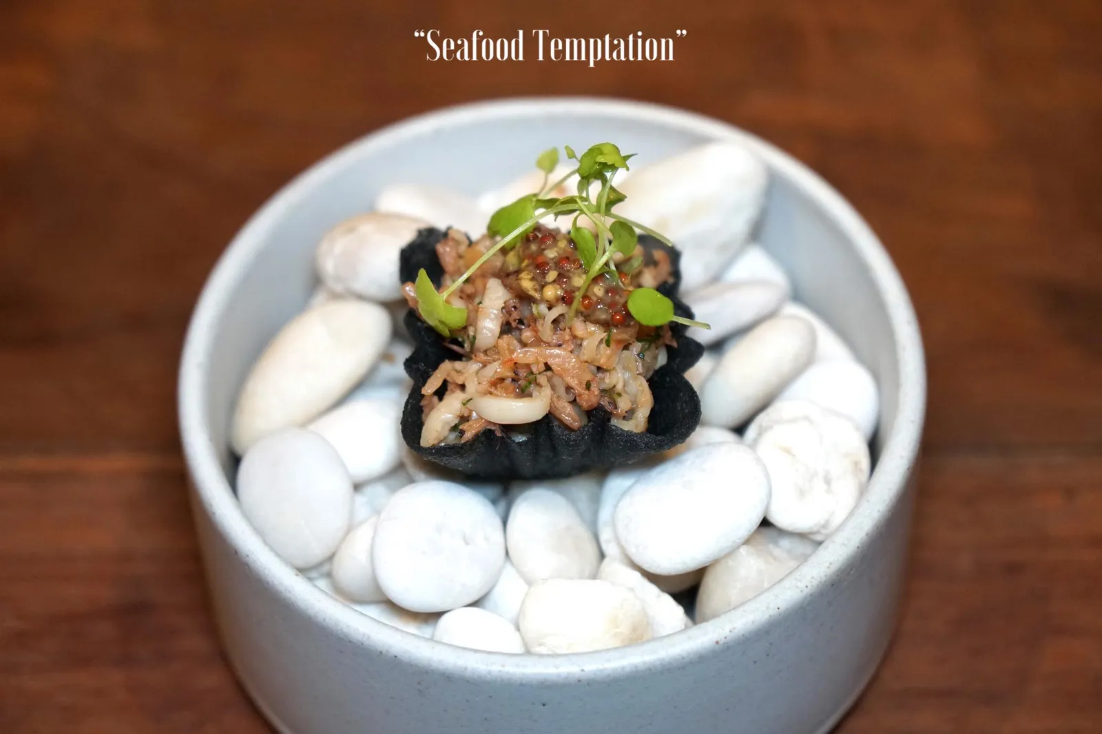 SEAFOOD TEMPTATION คำต่อมาคือ “หอยหลอด” จากเกาะเสร็จ อำเภอไชยา จังหวัดสุราษฎร์ธานี เสิร์ฟมากับเคยสดเป็นกุ้งตัวเล็กๆที่เห็นในภาพซึ่งเชฟแนนได้มาจากแหล่งเดียวกันกับหอยหลอด ปรุงรสด้วยมัสตาร์ดเกรนให้มีความเผ็ดเล็กน้อย ทั้งหมดใส่มาในกระทงทองชาโคล เวลาทานให้หยิบทานทั้งคำได้เลย กระทงทองชาโคลกรอบพอใช้ได้ กุ้งเคยให้รสมันเเละเค็ม มีกลิ่นหอม หอยหลอดจะมีเนื้อสัมผัสความหนึบเฉพาะตัว เราชอบที่เชฟนำมัสตาร์ดเกรนมาตัดให้จานนี้มีสีสันในตัวเองมากยิ่งขึ้น (13/20)