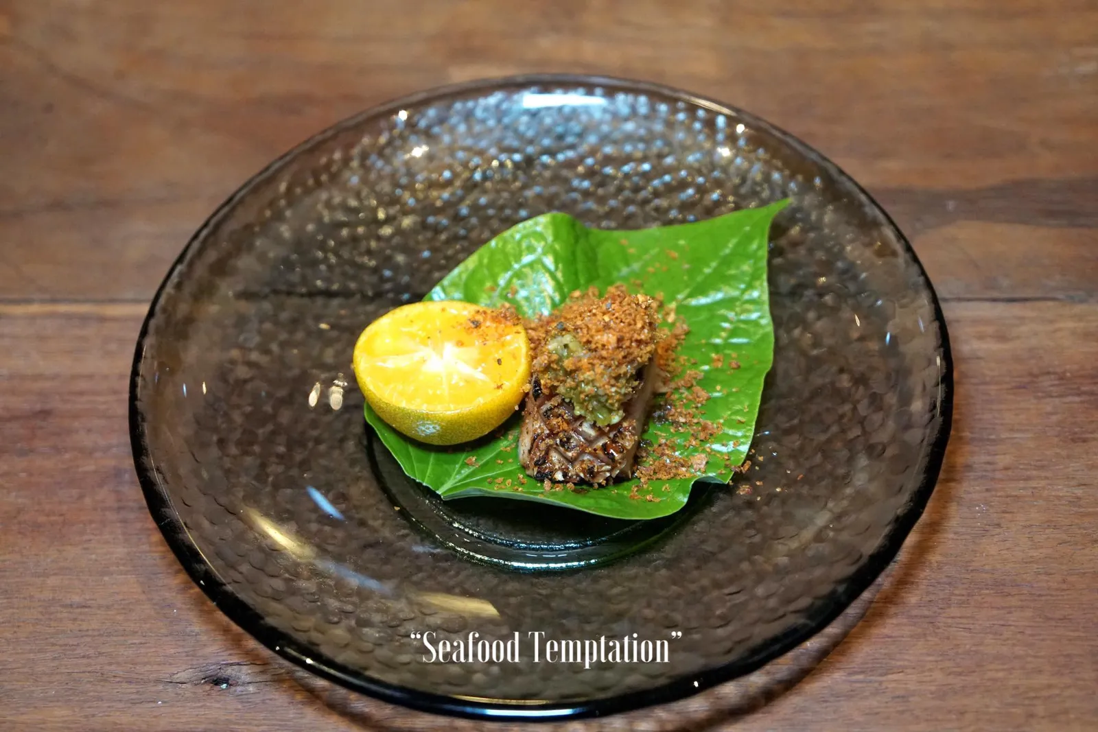 SEAFOOD TEMPTATION ถัดมาคือ “ปลากระบอก” จากจังหวัดสุราษฎร์ธานีที่เชฟนำมาอะบุริหรือทอร์ชไฟให้ผิวสุกด้านเดียวแบบญี่ปุ่น ด้านบนทอปด้วยน้ำพริกผักปลังที่มีเนื้อสัมผัสเหนียวหนึบ จุดนี้บอกได้เลยว่าจะมีทั้งคนที่ทั้งชอบเเละไม่ชอบ ผงสีเเดงด้านบนคือหนังปลากรอบปรุงรสด้วยองค์ประกอบบางส่วนของพริกหม่าล่า ก่อนทานให้บีบส้มจี๊ดลงไปแล้วใช้ใบชะพลูห่อทานเหมือนเที่ยงได้เลย เนื้อปลากระบอกนุ่ม สุกกำลังดี ตัดด้วยความกรอบของใบชะพลู รสชาติโดยรวมเน้นไปทางรสเปรี้ยวของน้ำส้มจี๊ด เเต่จะมีกลิ่นหอมของพริกหม่าล่าปนมานิดๆ (12/20)