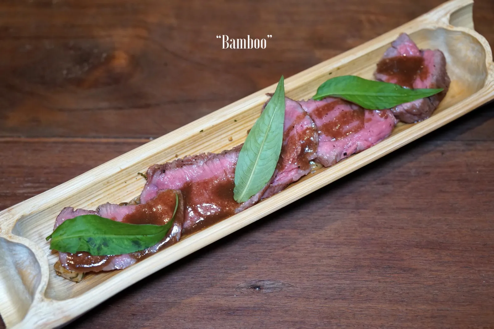 BAMBOO อาหารคาวจานสุดท้ายนำเสิร์ฟก่อนเข้าสู่อาหารหวานคือ “เนื้อย่างกำแพงแสน” เชฟแนนเลือกใช้เนื้อส่วนพื้นท้องไปย่างกับถ่านไม้ลำไยเสิร์ฟมาในกระบอกไม้ไผ่ที่ความสุกระดับมีเดียมแรร์ จานนี้ถือว่าทำออกมานุ่มใช้ได้เทียบกับความที่เป็นเนื้อวัวไทย ทานกับหน่อไม้ที่ทางร้านดองเอง มีความกรอบเเซมด้วยรสเปรี้ยวเพียงเบาๆ ด้านบนคือผักแพวให้ทานแนมกับตัวเนื้อด้วย (13/20)
