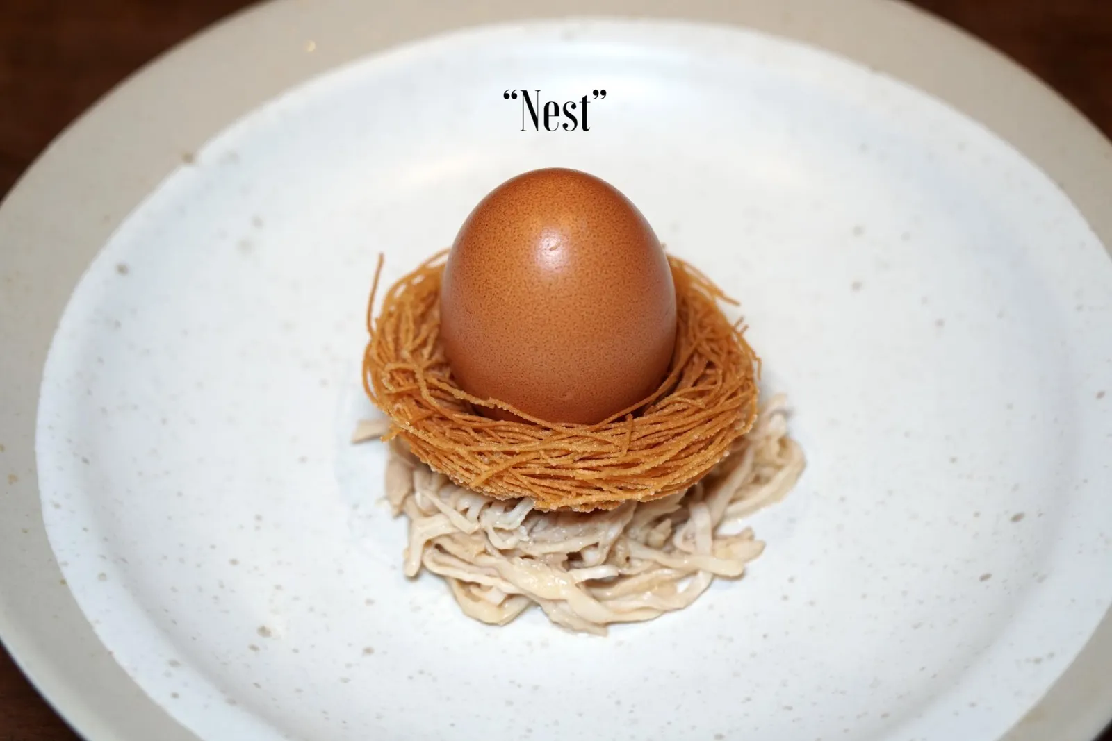 NEST ถัดมาคือ Signature Dish ที่ไม่เคยถูกถอดออกจากรายการเมนูและเป็นหนึ่งในสองจานที่นำเสิร์ฟคล้ายกันทั้งสาขากรุงเทพเเละเชียงใหม่ นั่นก็คือ “รังนก” ส่วนประกอบด้านบนคือไข่ไก่อารมย์ดีจากจังหวัดลำพูนไปเข้าเครื่องซูวีที่อุณหภูมิ 63.5 องศาเซลเซียสเป็นระยะเวลา 45 นาทีจนกลายเป็นไข่ออนเซ็น ชั้นกลางคือรังนกที่ทำมาจากเส้นหมี่ข้าวสวยนำไปทอดจนกรอบเพิ่มเนื้อสัมผัสให้กับจาน ด้านล่างคืออกไก่จากจังหวัดเชียงราย ฉีกเป็นชิ้นเล็กๆ เชฟนำไปผัดกับซอสโคจิที่ทางร้านหมักเองแล้วนำไปเคี่ยวกับกระดูกไก่อีกทีหนึ่ง (13/20)
