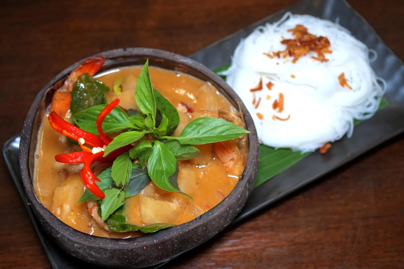 แกงคั่วสับปะรดกุ้งสดเสิร์ฟพร้อมเส้นหมี่ลวก (329) Pimeapple Curry with Shrimps แกงคั่วสับปะรดวันนี้เชฟลันไดบอกว่าสับปะรดที่ส่งมารสชาติไม่ค่อยเปรี้ยวนักทำให้แกงที่เราทานรสออกหวานนำแต่ไม่ค่อยอมเปรี้ยวซึ่งเป็นเสน่ห์ของแกงคั่ว เนื้อกุ้งนุ่ม สุกพอดี ทานคู่กับเส้นหมี่ดูจะเข้ากันมากกว่าข้าวสวย (11/20)