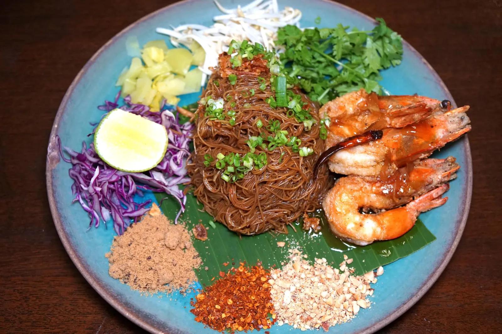 ผัดหมี่โบราณกุ้งทอดคลุกซอสมะขาม (199) Fried White Rice Noodles and Fried Shrimps with Tamarind Sauce เปิดฝาใบตองออกมาจะพบกับเส้นหมี่ที่ผัดกับน้ำซอสให้รสชาติคล้ายกับผัดซีอิ๊ว ฝั่งขวาคือกุ้งทอดเนื้อแน่น กรอบ เพื่อนๆสามารถเลือกทานกับเครื่องเคียงได้หลากหลายตามใจชอบมีทั้งพริก ถั่วบด มะนาว ผักดอง ซึ่งทำให้รสชาติในแต่ละคำที่ทานแตกต่างกันออกไป (12/20)