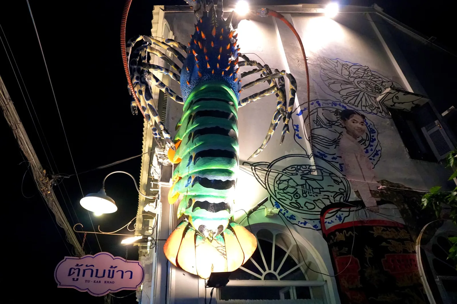 ตัวร้านตั้งอยู่บนถนนพังงา มองจากด้านหน้าเป็นอาคารเก่า 2 ชั้นสีขาวภายใต้สถาปัตยกรรมแบบชิโนโปรตุกีสอายุเกือบ 120 ปี หัวมุมร้านมีรูปปั้นของกุ้งมังกร 7 สีขนาดยักษ์ประดับอยู่