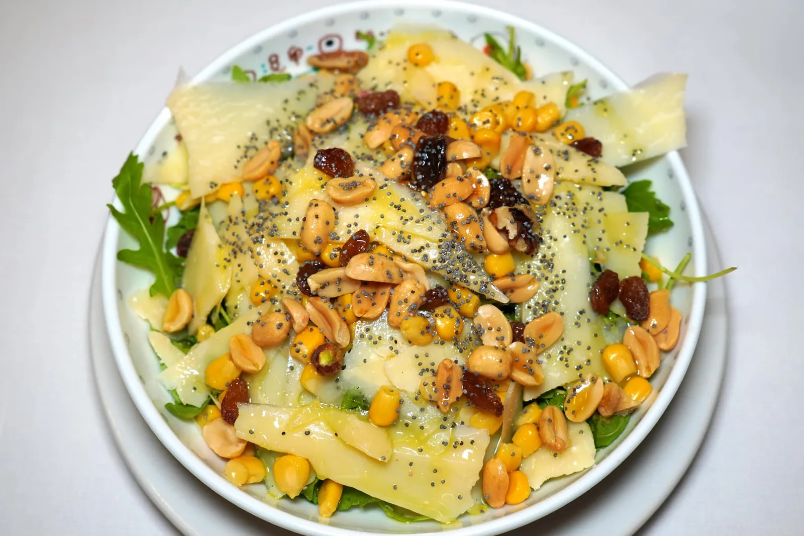 Insalata fantasia con rucola, parmigiano, mais, semi di papavero e misto di frutta a guscio (11 €) Salad with arugula, parmesan cheese, corn and mix of nuts and dried fruit เราแนะนำให้ตัดรสชาติของชีสด้วยสลัดแฟนตาซีที่ผสมทั้ง Arugula ข้าวโพด และถั่วหลากหลายชนิด และผลไม้แห้งเข้ากับชีส Parmesan (12/20)