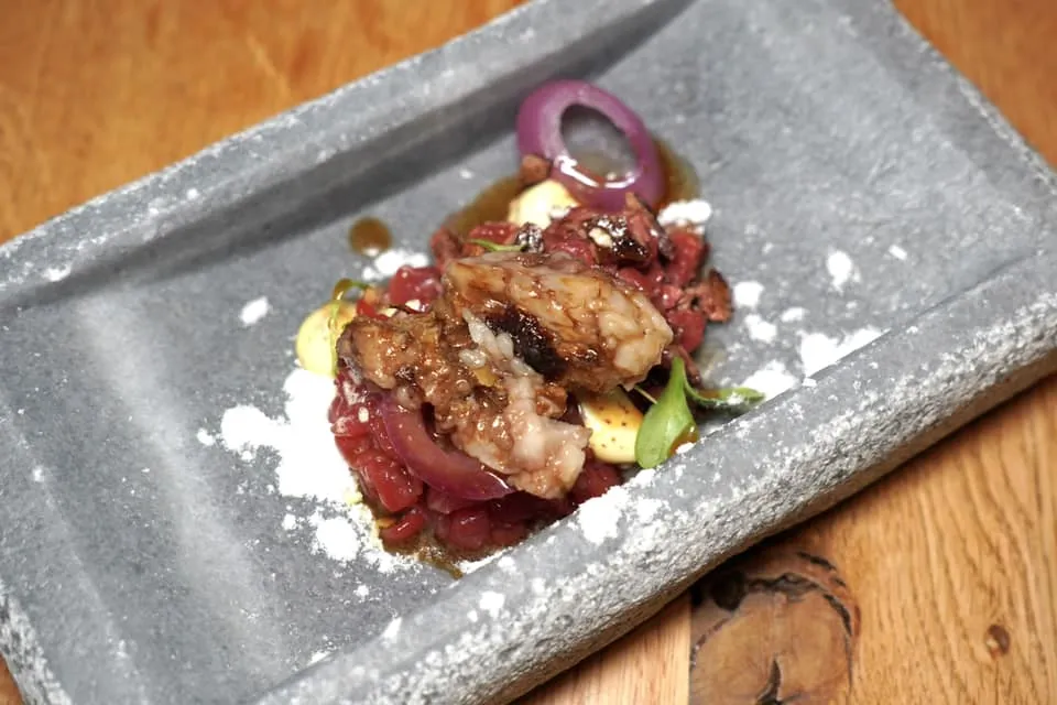 NON TOGLIERE L’OSSO A MARIO Barbecued Ossobuco with diaphragm, Piedmontese Fassona tartare Slow Food Presidium, spring onions, mustard mayonnaise and vinegar snow ในจานประกอบไปด้วยองค์ประกอบด้านล่างคือ Tartare ที่เตรียมมาจากเนื้อวัว Fassona ซึ่งเป็นสินค้าขึ้นชื่อของแคว้น Piedmont สับมาเป็นชิ้นเสิร์ฟ Rare จับคู่กับเนื้อส่วนกระบังลมย่างที่ความสุกระดับ Medium Rare ด้านบนท็อปด้วยผงหิมะสีขาวที่เตรียมมาจากน้ำส้ม ยังมีองค์ประกอบของซอสมัสตาร์ดมาโย และซอสเนื้อรสชาติเข้มข้นเทราดลงไปแล้วจบด้วยการบรรจงวางไขกระดูกวัวลงไปนั่นเอง (15/20)
