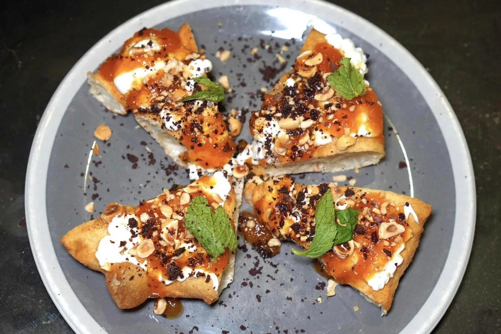LA CRISOMMOLA DEL VESUVIO Slice of fried pizza with lemon peels flavoured DOP buffalo ricotta cheese, Vesuvio apricot jam, roasted hazelnuts, Caiazzo dehydrated olives, fresh mint พิซซ่าหน้าอาหารหวานที่กลายมาเป็นเมนูเด็ดประจำร้านนี้เกิดขึ้นเมื่อเกษตรกรท้องถิ่นของภูมิภาค Campania ได้แบก Apricot กองโตที่ปลูกและเติบโตบนดินภูเขาไฟ Vesuvius มาปรึกษาเชฟ Franco Pepe เพื่อหาทางในการเพิ่มมูลค่าสินค้า เชฟจึงตัดสินใจนำ Apricot คุณภาพดีเหล่านั้นมาทำเป็นแยมก่อนจะนำไปทาลงบนพิซซ่าทอดที่มีความเบากรอบเสริมด้วยความขมที่ลงตัวของเปลือกเลมอน เชฟใส่ชีส Ricotta นมควายลงไปเพื่อบาลานซ์รสชาติความหอมมันและลดทอนความจัดจ้านของ Apricot ยังมีความกรอบจากถั่วฮาเซลนัทคั่ว และอโรมาเฉพาะตัวของมะกอกดำที่ผ่านกระบวนการ Dehydrated จนแห้งโรยลงไปทั่ว ๆ สุดท้ายเชฟวางใบมิ้นต์ลงไปเพื่อช่วยเพิ่มความสดชื่นให้กับจานได้อีกด้วย (15/20)