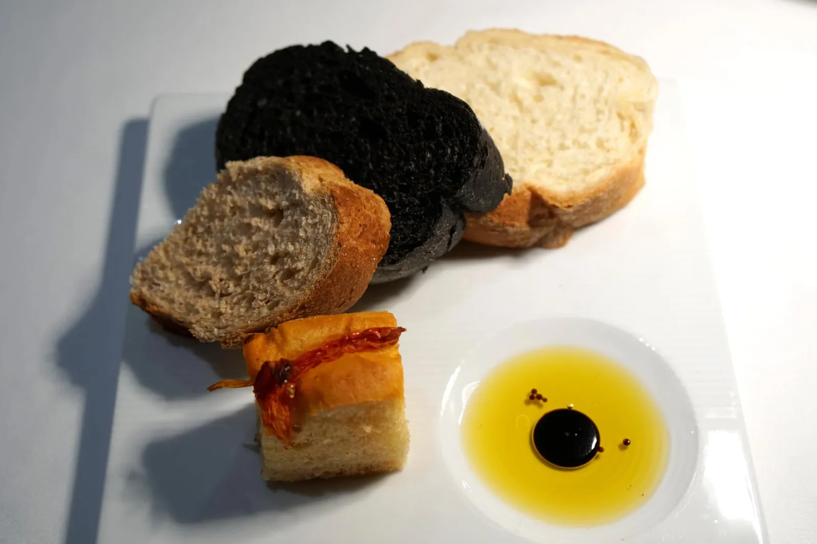 Italian Bread with Extra Virgin Olive Oil Whole Wheat, White Bread, Black Ink, Focaccia, Grissini ทางร้านนำเสิร์ฟขนมปังสี่อย่างคือขนมปังธรรมดา ขนมปังโฮลวีท ขนมปังหมึกดำ และโฟกาซเชีย ทานกับน้ำมันมะกอกเอ็กซ์ตร้าเวอร์จิ้นเเละน้ำส้มสายชูบัลซามิค (12/20)