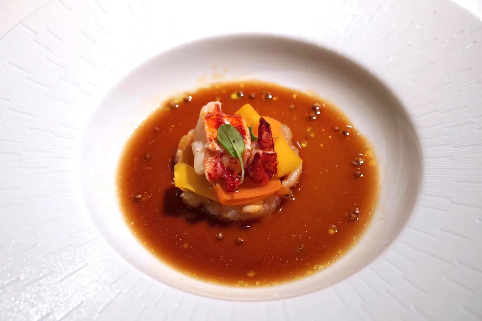 'Lobster / carrot', lobster jus, toasted buckwheat «Homard-carottes» au jus de homard et sarrasin torréfié Medallions of lobster with carrot ribbons and a lobster salpicon; 'dry vinaigrette' of lobster and carrot, lobster cream and toasted buckwheat. ถัดมาเป็นคอร์สที่จับคู่วัตถุดิบสองชนิดคือ “ล็อบสเตอร์และแครอท” มาไว้ในจานเดียวกัน เพียงเชฟยกมาวางเราก็สัมผัสได้ถึงกลิ่นหอมอันเด่นชัด องค์ประกอบแรกของจานคือซัลปิคอนล็อบสเตอร์คลุกกับล็อบสเตอร์ครีมแล้วเสิร์ฟมาแบบดิบคล้ายทาทาร์ น้ำสีส้มรอบ ๆ คือ Bouillon หรือวินิแกรตแห้งทำมาจากล็อบสเตอร์และแครอทเช่นกัน ด้วยรสชาติที่ออกไปทางเปรี้ยวจึงช่วยดึงรสหวานธรรมชาติจากล็อบสเตอร์ออกมาได้ดี เชฟเพิ่มมิติทางเนื้อสัมผัสโดยการใส่เมล็ดบัควีทที่ผ่านการคั่วจนแห้งลงไปด้วย เวลาเคี้ยวก็จะได้ความกรอบมาตัดกับความนุ่มและเด้งของเนื้อกุ้ง เลเยอร์ตรงกลางเป็นแครอททั้งสุกและดิบฝานมาบาง ๆ เป็นริบบิ้นสวยงามเพิ่มมิติความกรอบ สุดท้ายคือ Lobster Medallions หรือเนื้อล็อบสเตอร์แบบสุกเสิร์ฟเป็นชิ้นวางด้านบน ตักทานทุกองค์ประกอบพร้อมกันเพื่อให้ได้รสชาติและเนื้อสัมผัสอันซับซ้อน (20/20)